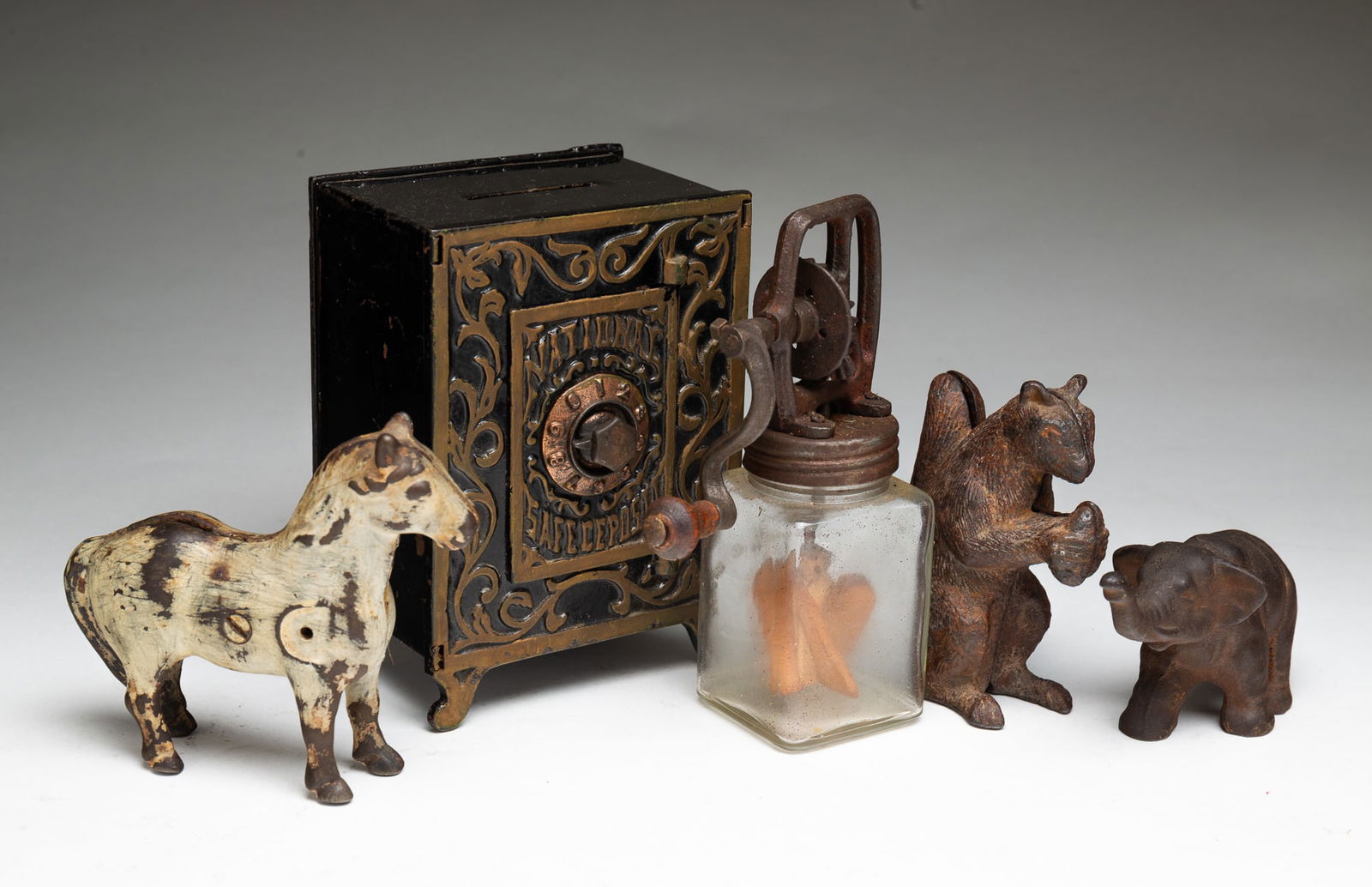 FIVE AMERICAN DIMINUTIVE DECORATIVE ITEMS.: American, ca. 1900. Including a metal National Safe Deposit safe form bank, 6"h. 4.25"w., a cast iron elephant figurine, 2.25"h., a miniature churn by "Dazey Churn Mfg. Co.", 7"h., a cast iron "Good L