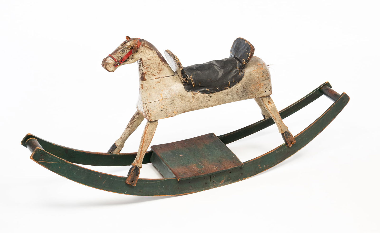 AMERICAN CARVED AND PAINTED WOOD ROCKING HORSE.: American, Early 20th Century. Pine. Multi-section horse with gray paint, minimal horse hair tail, rivet eyes, leather ears, black leather saddle with seat and leather trim and base with worn green pai
