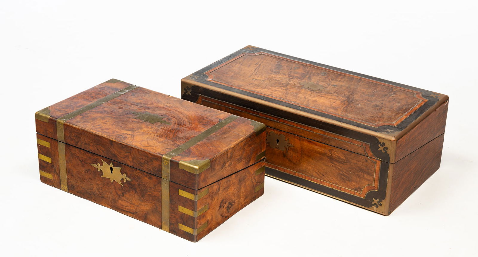 TWO ENGLISH LAP DESKS.: England, 19th Century. One is rosewood with mahogany and ebony banded inlay, brass corners and wire inlay and interior wells and slanted writing surface. 7"h. 20"w. 10.5"d. And the second is burled ve