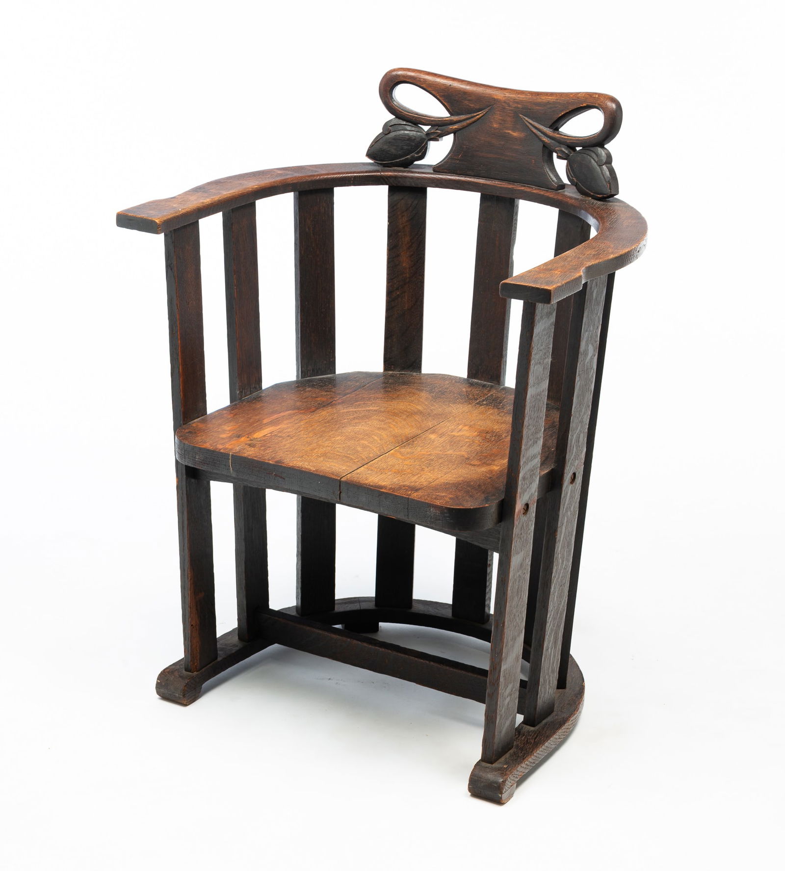 ATTRIBUTED TO STICKLEY BROTHERS (GRAND RAPIDS, MICHIGAN) ARTS AND CRAFTS CARVED AND QUARTERSAWN OAK: Attributed to Stickley Brothers (Grand Rapids, Michigan), Early 20th Century. Oak. Fancy carved crest rail, rounded vertical slat back with flat arms, and resting on a horseshoe form base. 33"h. 25"w.