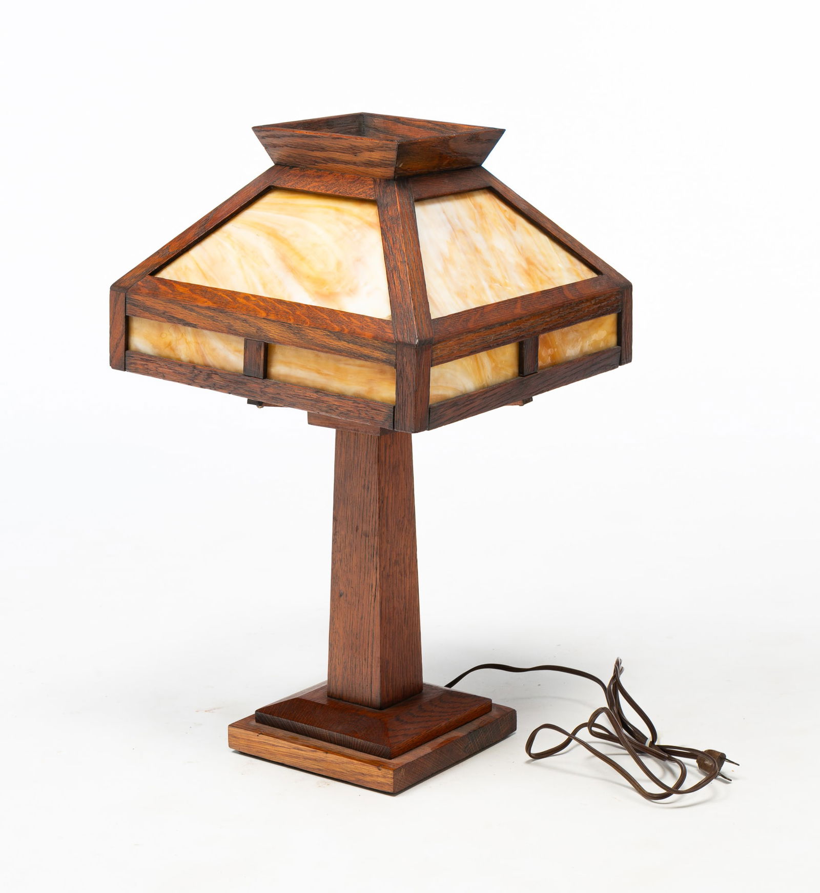 AMERICAN ARTS AND CRAFTS OAK AND SLAG GLASS TABLE LAMP.: American, Early 20th Century. Oak. Square base with tapered column, square shade with caramel slag glass panels and flared top. Original pull. 20.5"h. 12" square.