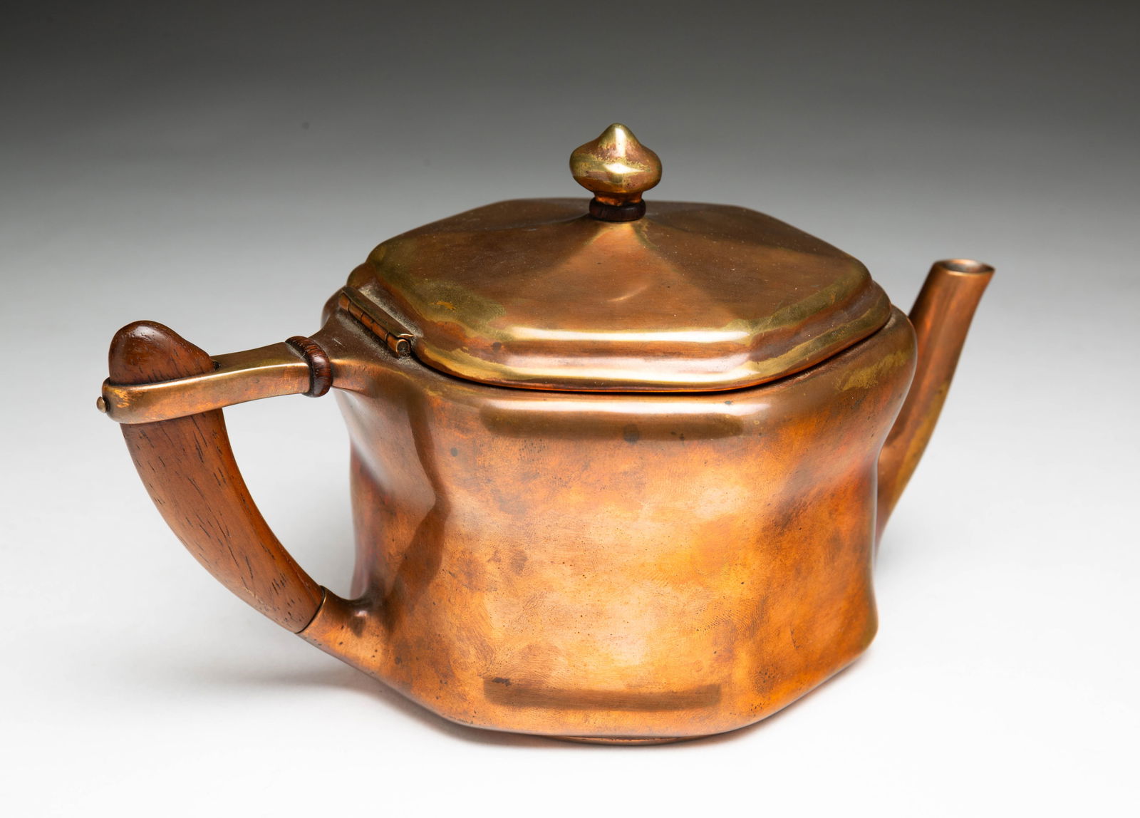 TIFFANY STUDIOS (NEW YORK, NEW YORK) ARTS AND CRAFTS COPPER TEAPOT.: Tiffany Studios (New York, New York), Early 20th Century. Of hexagonal form with a wooden handle, signed "Tiffany Studios New York" on underside. 4.75"h. 8"w.
