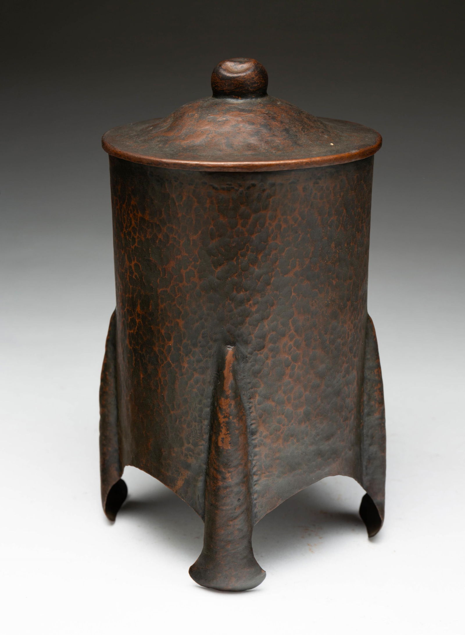 AMERICAN ARTS AND CRAFT HAMMERED COPPER HUMIDOR.: American, 20th Century. Of cylindrical form and having four legs. 7.5"h. 4.25"d.