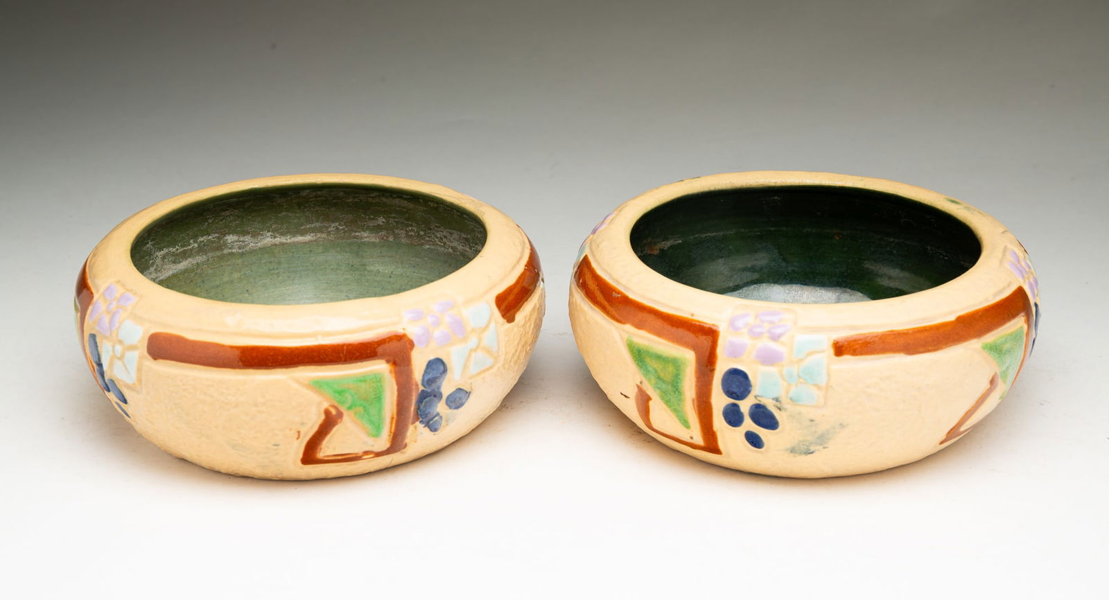 TWO ROSEVILLE POTTERY CO. (ROSEVILLE, OHIO) "MOSTIQUE" BOWLS.: Roseville Pottery Company (Roseville, Ohio), Early 20th Century. Squat round forms with decorated flower patterns to exterior and green interior. 2.5"h. 6.5"d. and 2.75"h. 7"d.