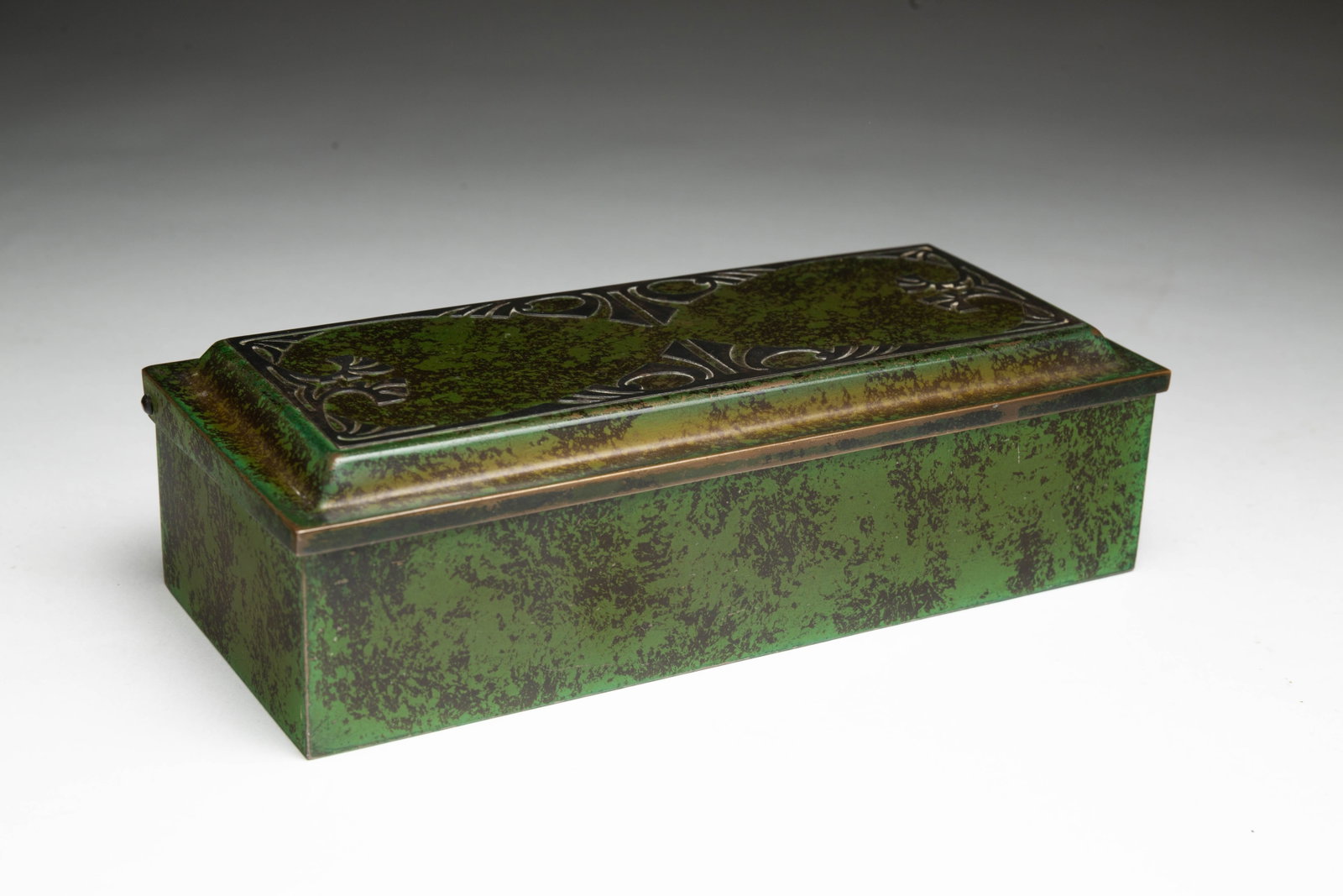 HEINTZ (BUFFALO, NEW YORK) ARTS AND CRAFTS STERLING-MOUNTED BRONZE CIGARETTE BOX.: Heintz (Buffalo, New York), ca. 1912. Of rectangular form, having a hinged lid decorated with a sterling floral motif on patinated bronze box with verdigris patina, the interior lined with cedar, mark