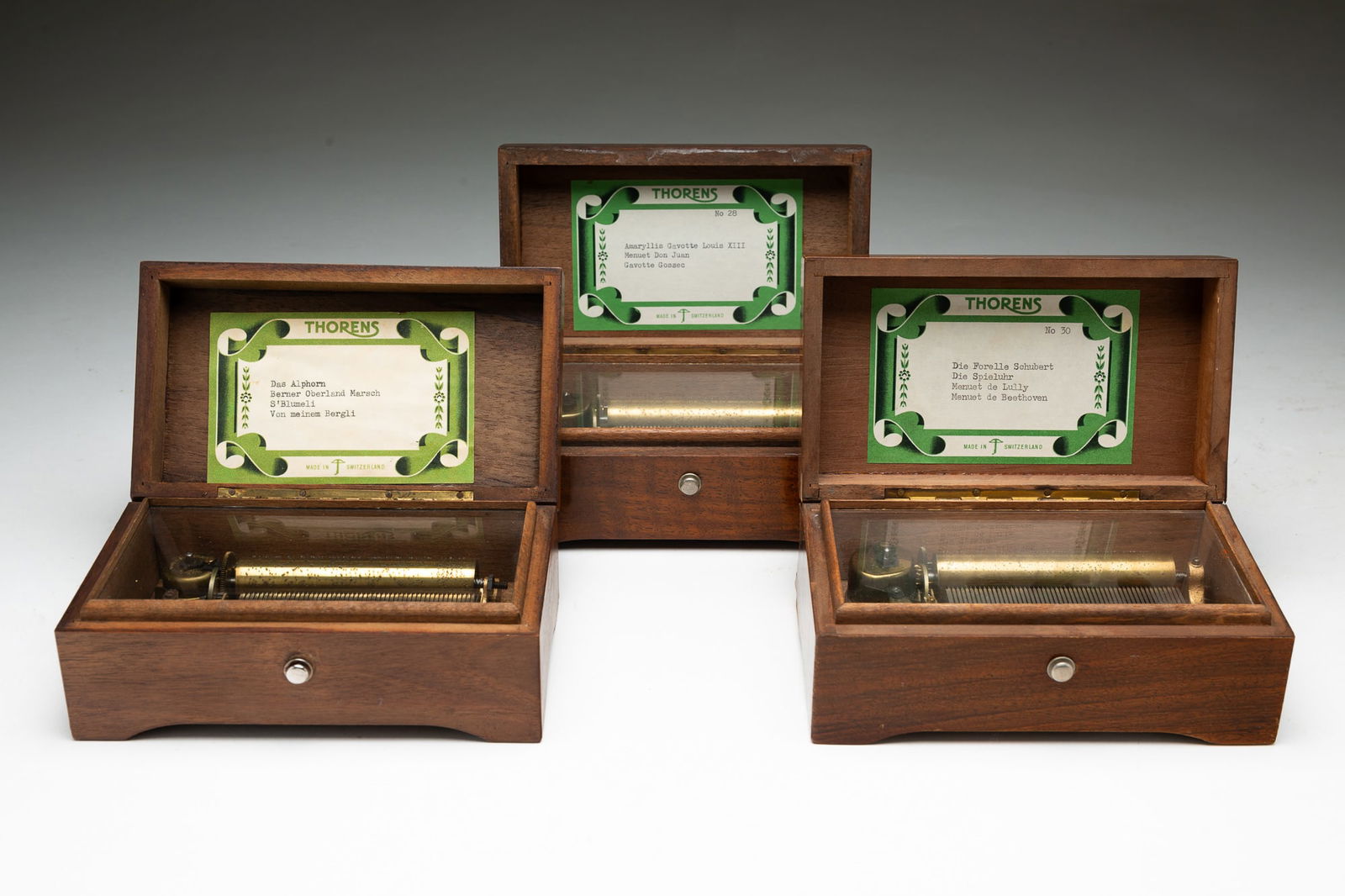 THREE THORENS WALNUT MUSIC BOXES.: Swiss, 20th Century. Walnut. Three identical boxes with shield inlay on top. One is fifty-six notes and plays three tunes. The second is fifty-six notes and plays three tunes. And the third is fifty s