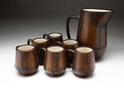 SEVEN-PIECE CHARLES CLEWELL (CANTON, OHIO 1876-1965) ARTS AND CRAFTS COPPER-CLAD CERAMIC CIDER SET.