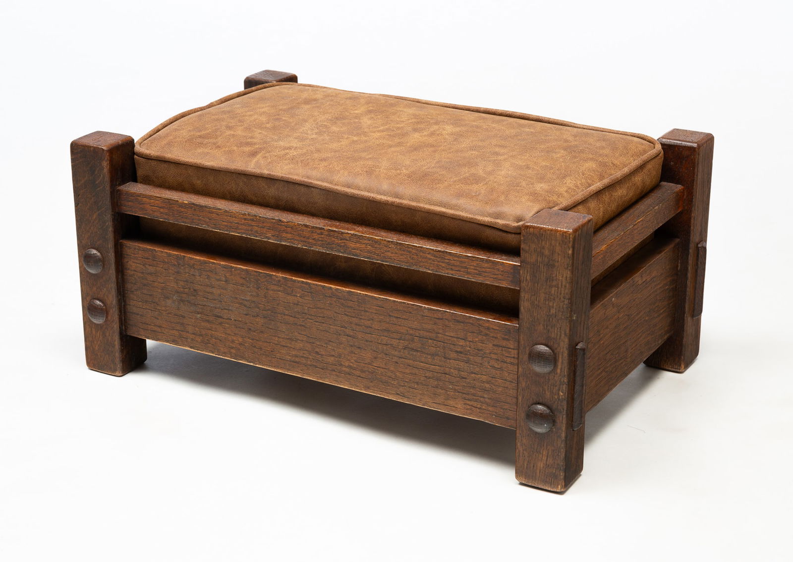 STICKLEY BROTHERS (GRAND RAPIDS, MICHIGAN) ARTS AND CRAFTS "NO. 5674" OAK AND LEATHER FOOTSTOOL.: Stickley Brothers (Grand Rapids, Michigan), Early 20th Century. Oak. Loose tan leather cushion. Rectangular form. Original finish and exposed tenons. 9"h. 19"w. 12"d.