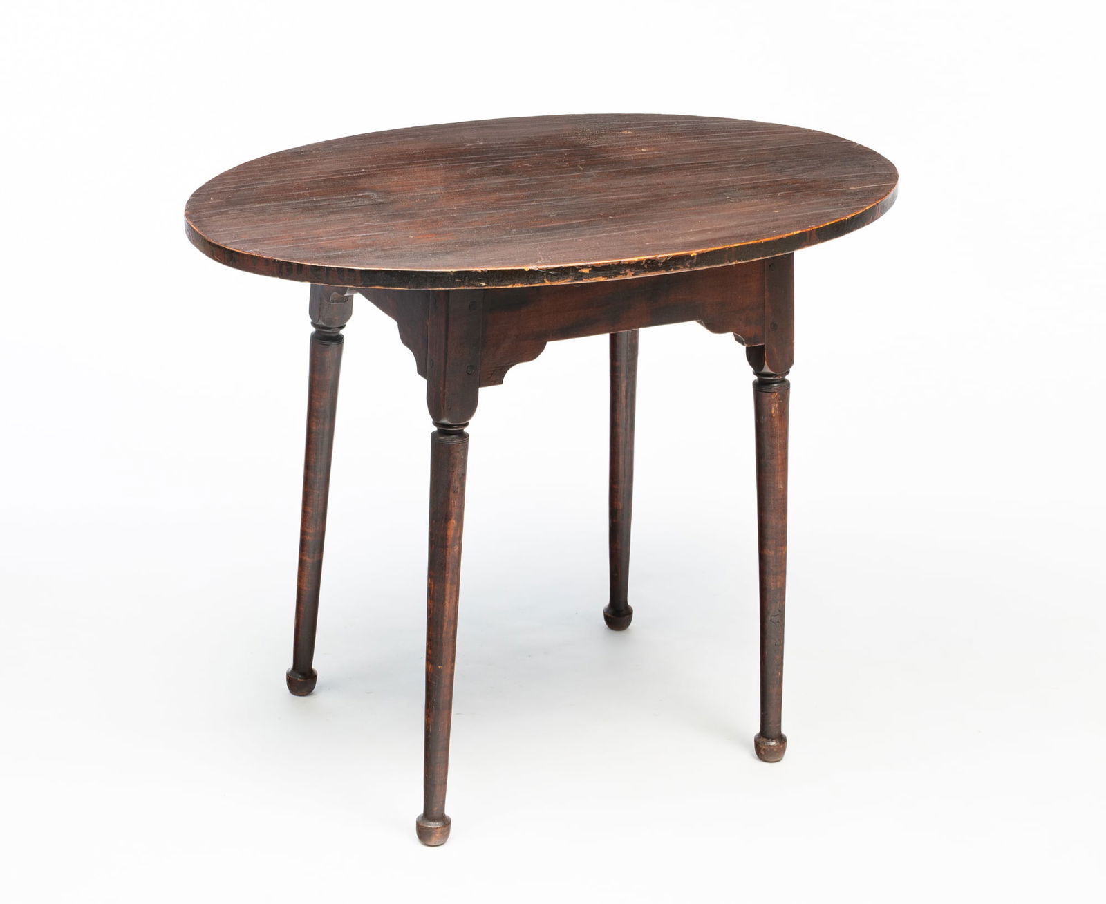 AMERICAN QUEEN ANNE POPLAR AND BIRCH TEA TABLE.: American, Mid-18th Century. Poplar and birch. Oval top, shaped apron, tapered turned splayed legs, pad feet and pegged construction. Older dark finish. 26.5"h. 32.5"w. 22"d.Provenance: From the Lifeti