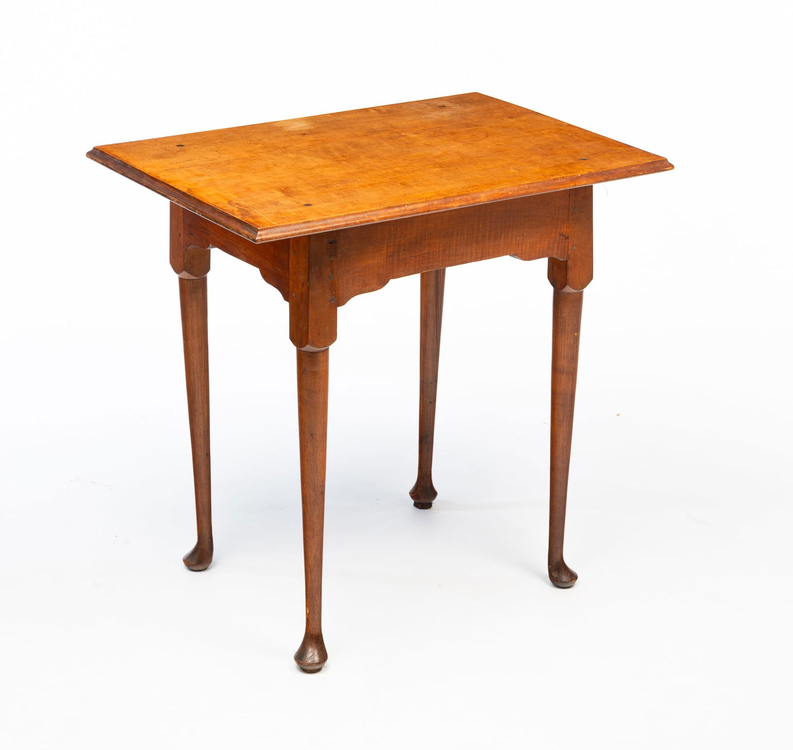 AMERICAN QUEEN ANNE BIRCH AND MAPLE TEA TABLE.: American, 18th Century. Birch and maple. Two-board top with routed edge, base with shaped apron, tapered turned legs, pad feet and pegged construction. 24.75"h. 27.5"w. 19"d.Provenance: From the Lifet