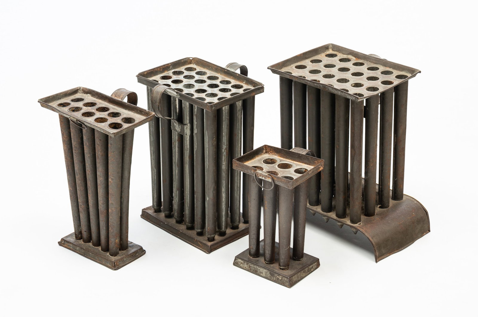 FOUR TIN CANDLE MOLDS.: American, Mid-19th Century. A four tube, 7.25"h, a ten tube, 10"h., and two twenty-four tubes, 11.5"h. and 10.5"h.Provenance: From the Lifetime Collection of the late Joanne & David Hill (Arcanum, Ohi