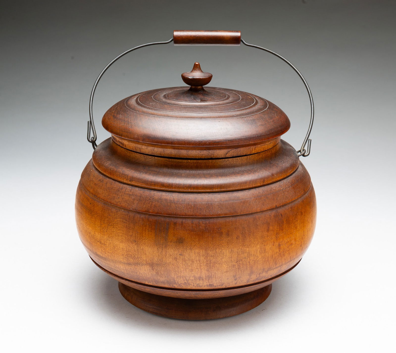 LARGE PEASEWARE LIDDED JAR WITH BAIL HANDLE.: American (Ohio), 19th Century. Turned wood jar having a lid with urn finial and rings, a bulbous body with rings at neck and base, and having a pronounced foot. With handle, 9"h. 7"d.Provenance: From