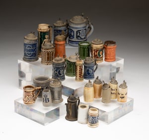 TWENTY-FIVE MINIATURE STONEWARE STEINS.