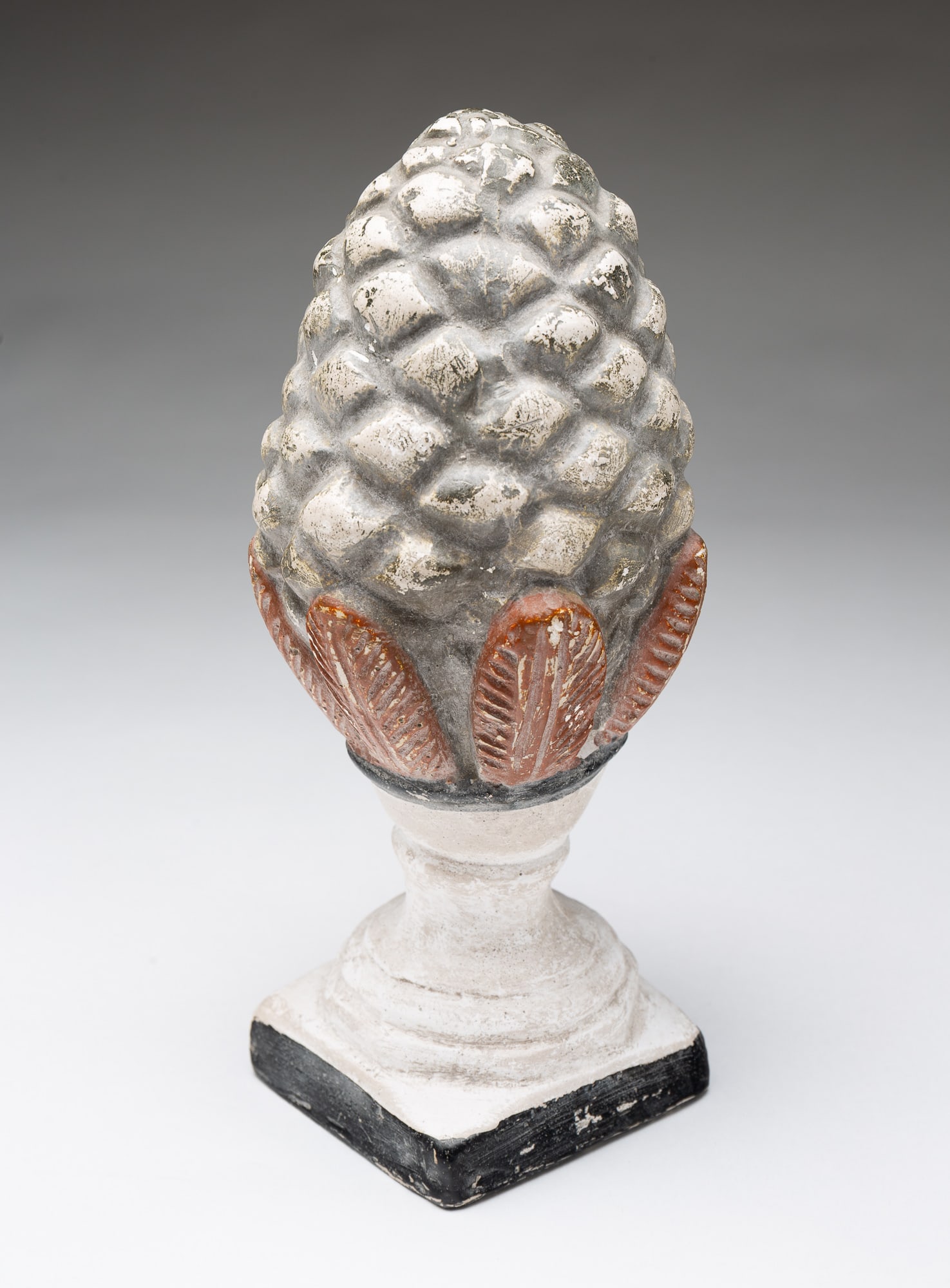AMERICAN CHALKWARE PINECONE ON PEDESTAL.: American, Early 20th Century. Hollow chalkware pinecone on pedestal with red, black and gray paint decoration. 9"h.Provenance: From the Lifetime Collection of the late Joanne & David Hill (Arcanum, Oh