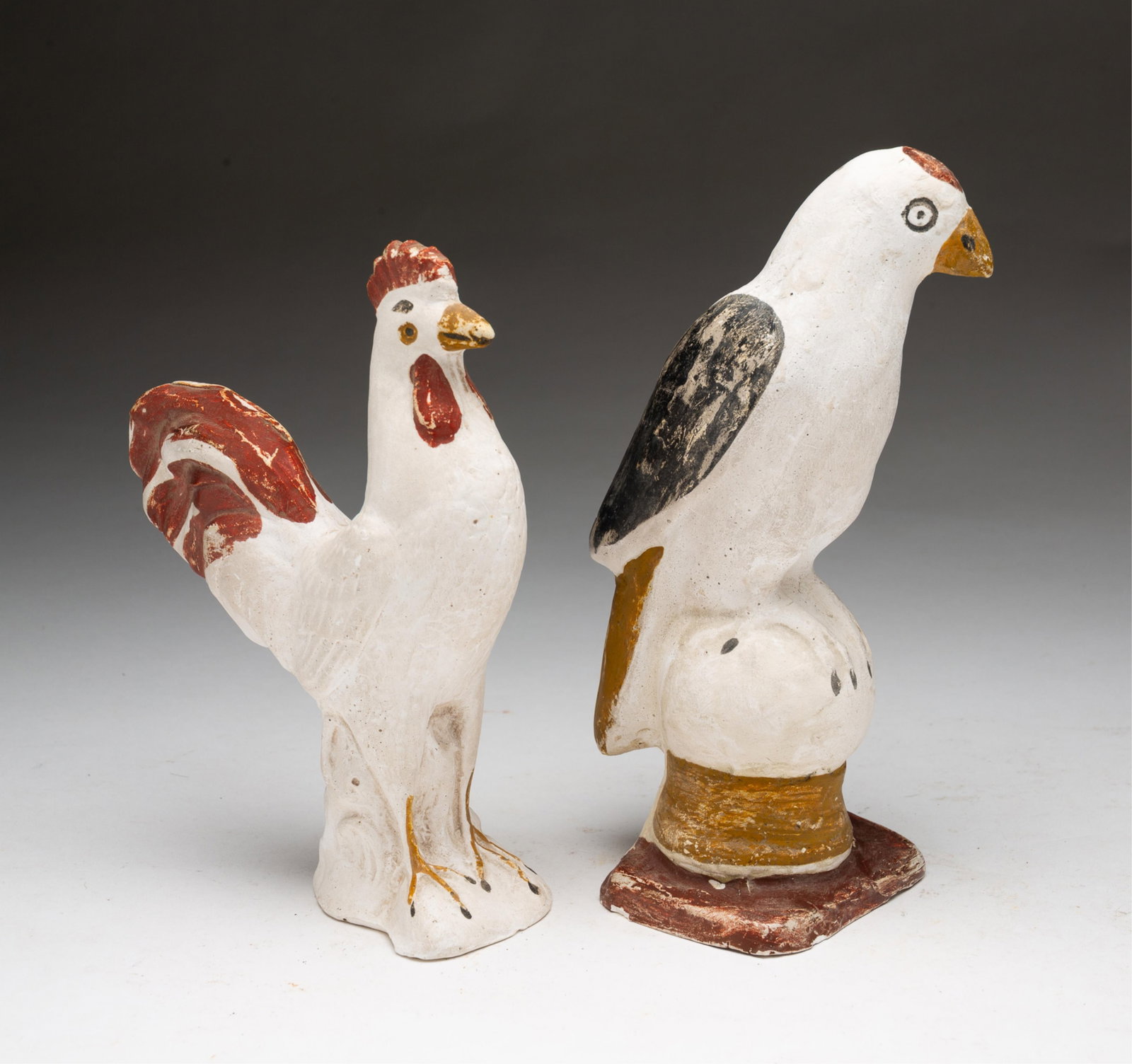 PENNSYLVANIA CHALKWARE BIRD AND ROOSTER: American (Pennsylvania), 19th Century. White bird with red patch on head, black wings, and yellow beak perched on a white sphere and yellow and red rectangular base. 8.25"h. Standing white rooster wit