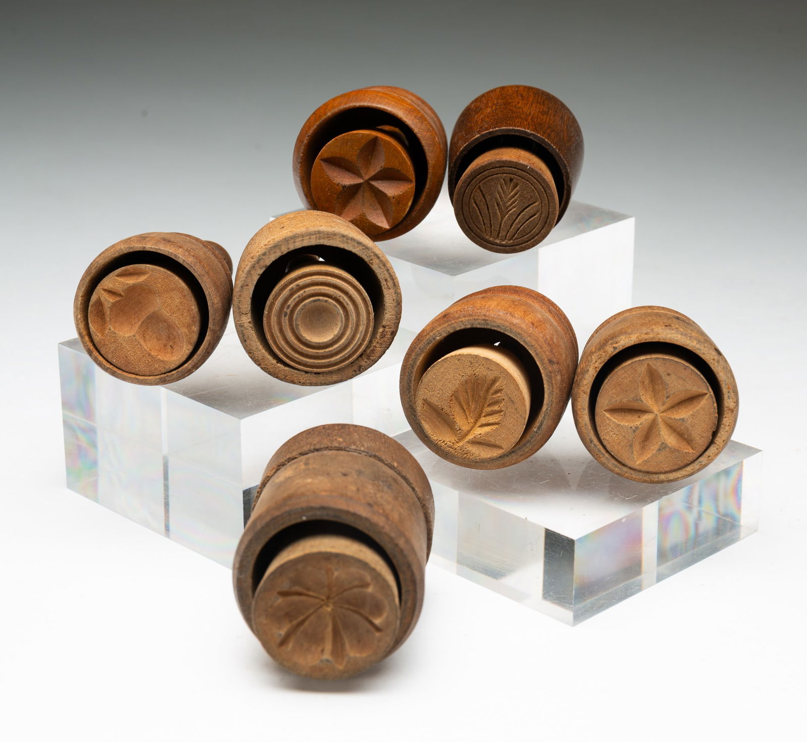 SEVEN DIMINUTIVE BUTTER PRINTS OR STAMPS.: American, 19th Century. Mixed woods. Carved stamps comprising an acorn, a flower, a sprig of grain, concentric circles, and three stylized floral motifs. Tallest, 3.5"h.Provenance: From the Lifetime C