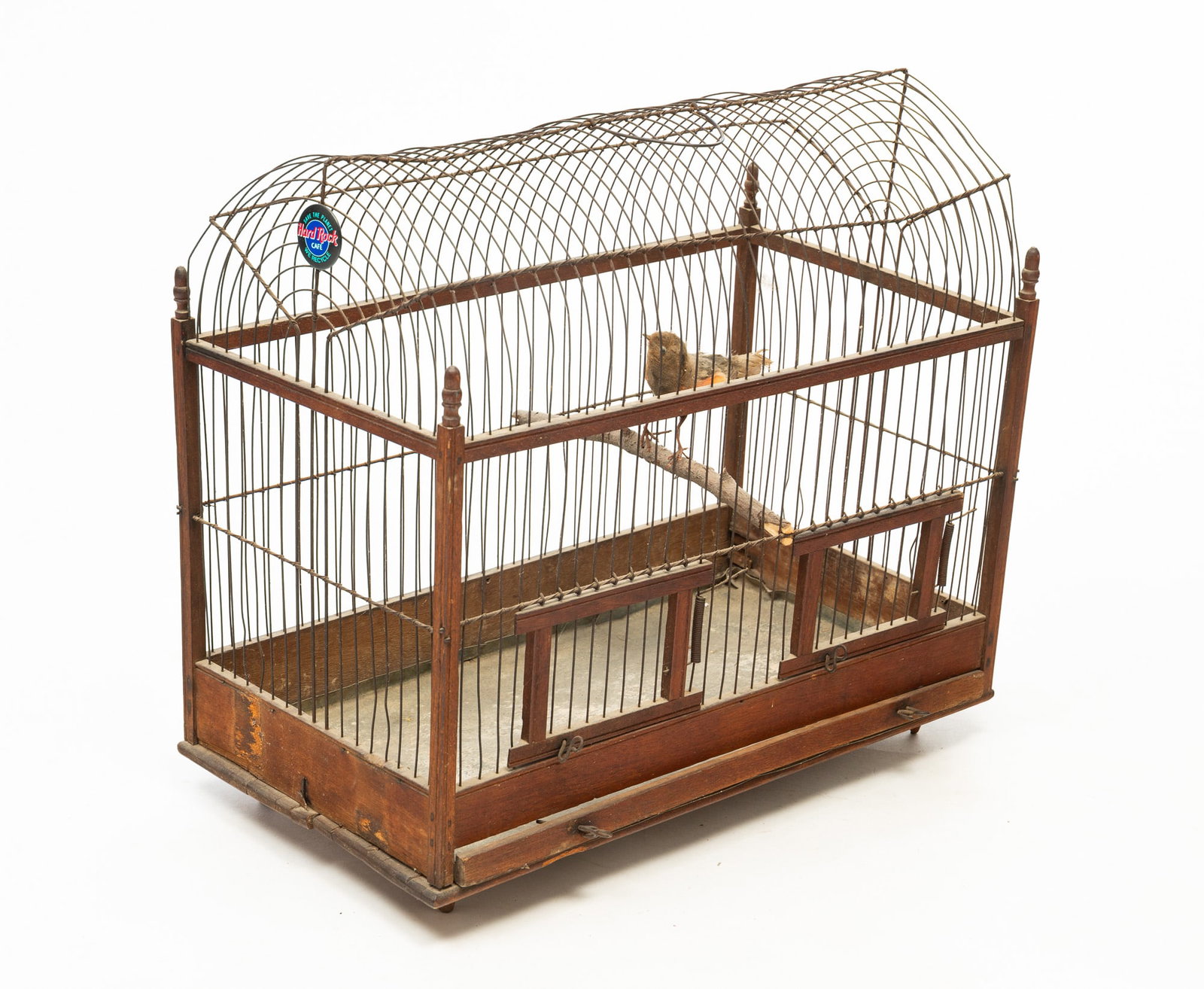VICTORIAN PINE AND WIREWORK DOME TOP BIRDCAGE.: American, Late 19th Century. Pine and wire. Wire dome top bird cage with handle, two doors, and a single bird on a branch. 18"h. 18.25"w. 10"d.Provenance: From the Lifetime Collection of the late Joan