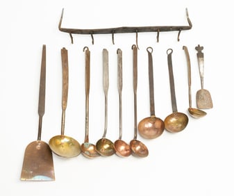 NINE DIMINUTIVE BRASS AND COPPER DIPPERS AND SPATULAS WITH IRON HANGING RACK.