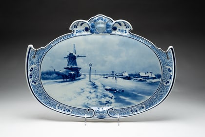 AFTER LOUIS APOL (DUTCH, 1850-1936) DELFT PORCELAIN WALL PLAQUE WITH WINTER SCENE.