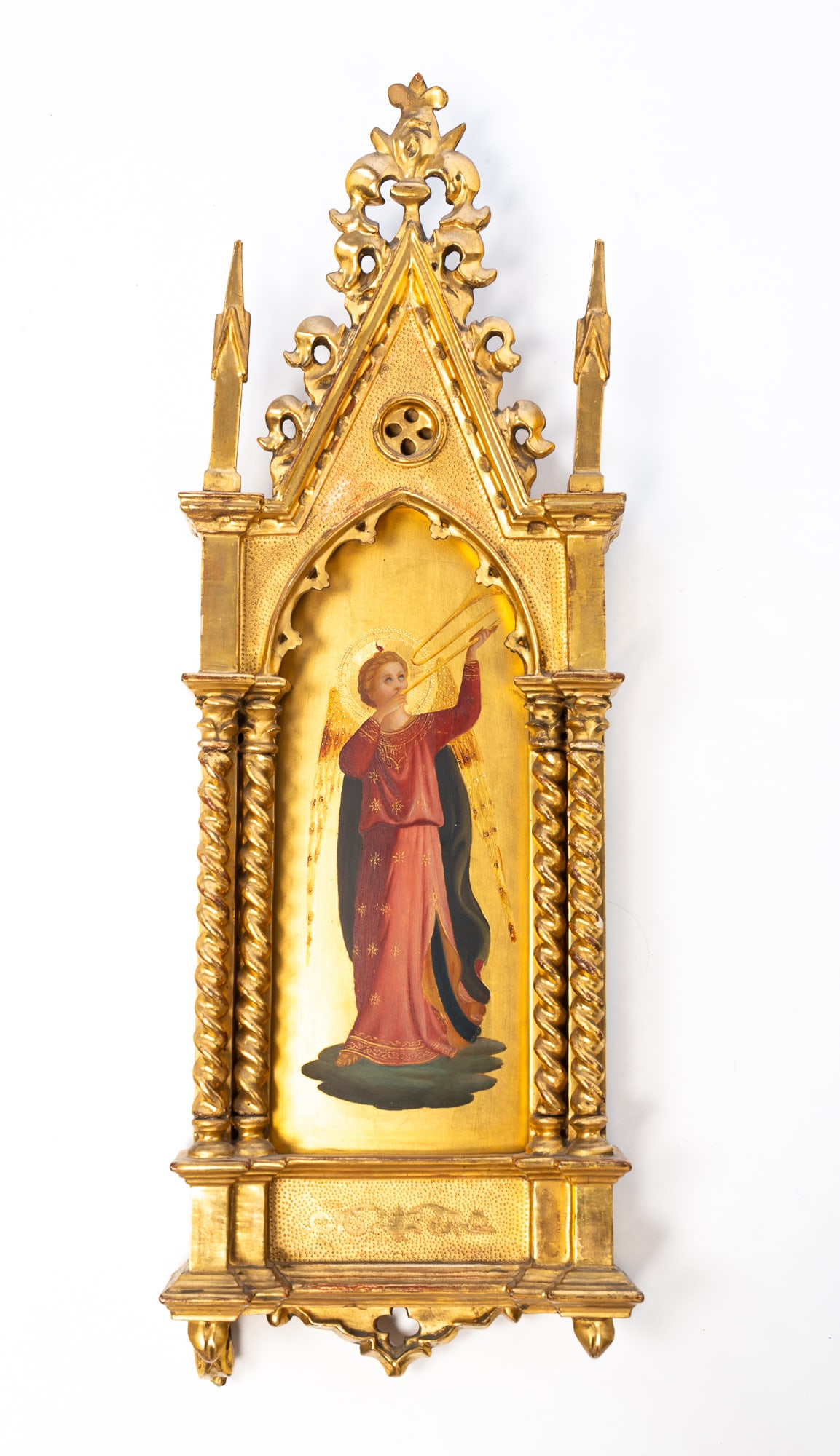 AFTER FRA ANGELICO (ITALIAN, 1395-1455) TEMPERA AND GILT ON PANEL OF AN ANGEL HOLDING A TRUMPET IN: Italy, ca. 1900. Tempera and gilt on panel. Depicting an angel with wings in a red gown holding a trumpet aloft, housed in an ornately carved gold leaf Gothic frame. 25"h. 8.75"w.Provenance: From the
