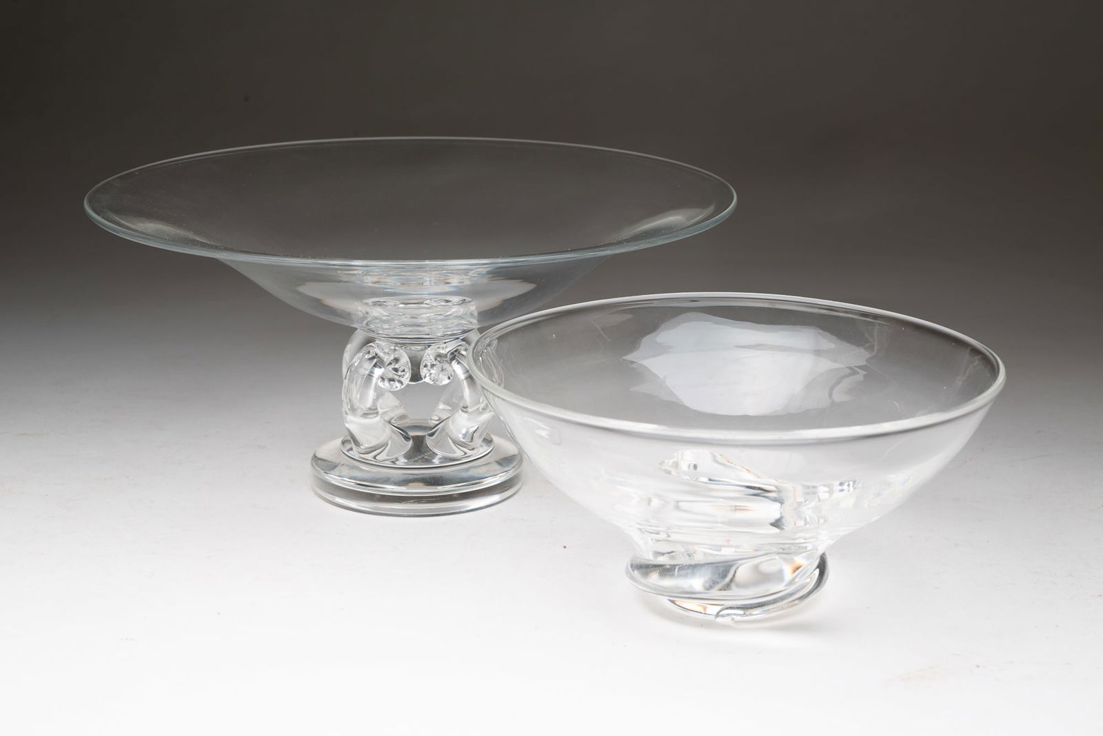 STEUBEN (CORNING, NEW YORK) ART GLASS BOWL AND COMPOTE.: Steuben (Corning, New York), 20th Century. Bowl with round form and swirl base. Signed to bottom. 3.5"h. 7.25"d. And a round form compote with openwork center pedestal and a round base. Signed to bott
