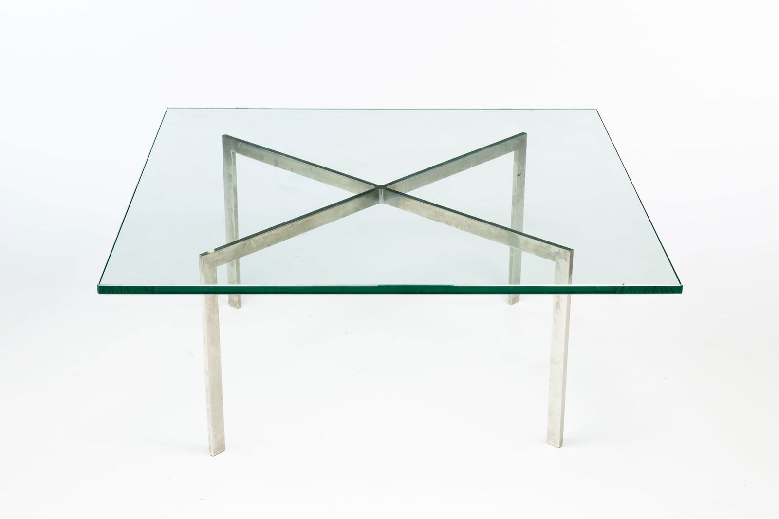 MIES VAN DER ROHE (1886-1969) FOR KNOLL MODERNIST CHROME AND GLASS TOP "BARCELONA" COFFEE TABLE.: Mies van der Rohe (German-American, 1886-1969) for Knoll Associates, ca. 1970. Steel and glass. Having a thick, beveled glass top above a chrome, X-form base. 17"h. 40"w. 40"d.Provenance: From The Lif