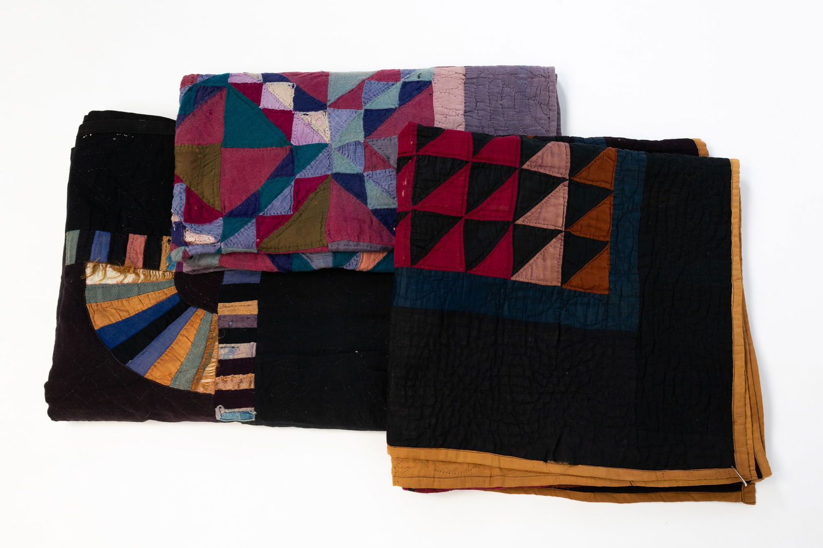 THREE AMISH QUILTS.: Amish (likely Ohio), Late 19th to early 20th Century. Cotton and wool. The first a cotton "Diagonal Triangles" crib quilt having polychrome diamonds on a black ground within a navy blue border. Approx