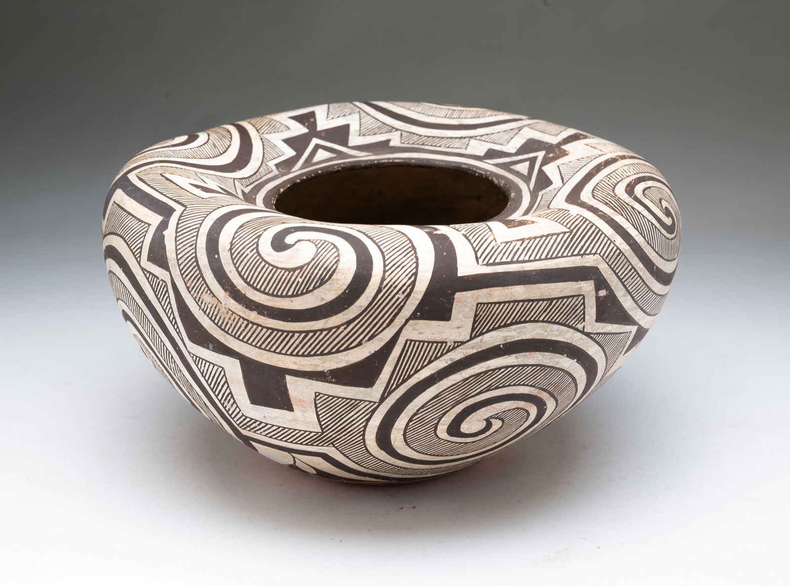 ATTRIBUTED TO JUANITA JOHNSON (ACOMA PUEBLO, B. 1883/1891) POLYCHROME POTTERY JAR.: Attributed to Juanita Johnson (Acoma Pueblo, born 1883/1891), ca. 1920. Thin-walled pottery vessel decorated in black and white swirls and geometric designs having an inverted top rim. 5.5"h. 11"d.Pro