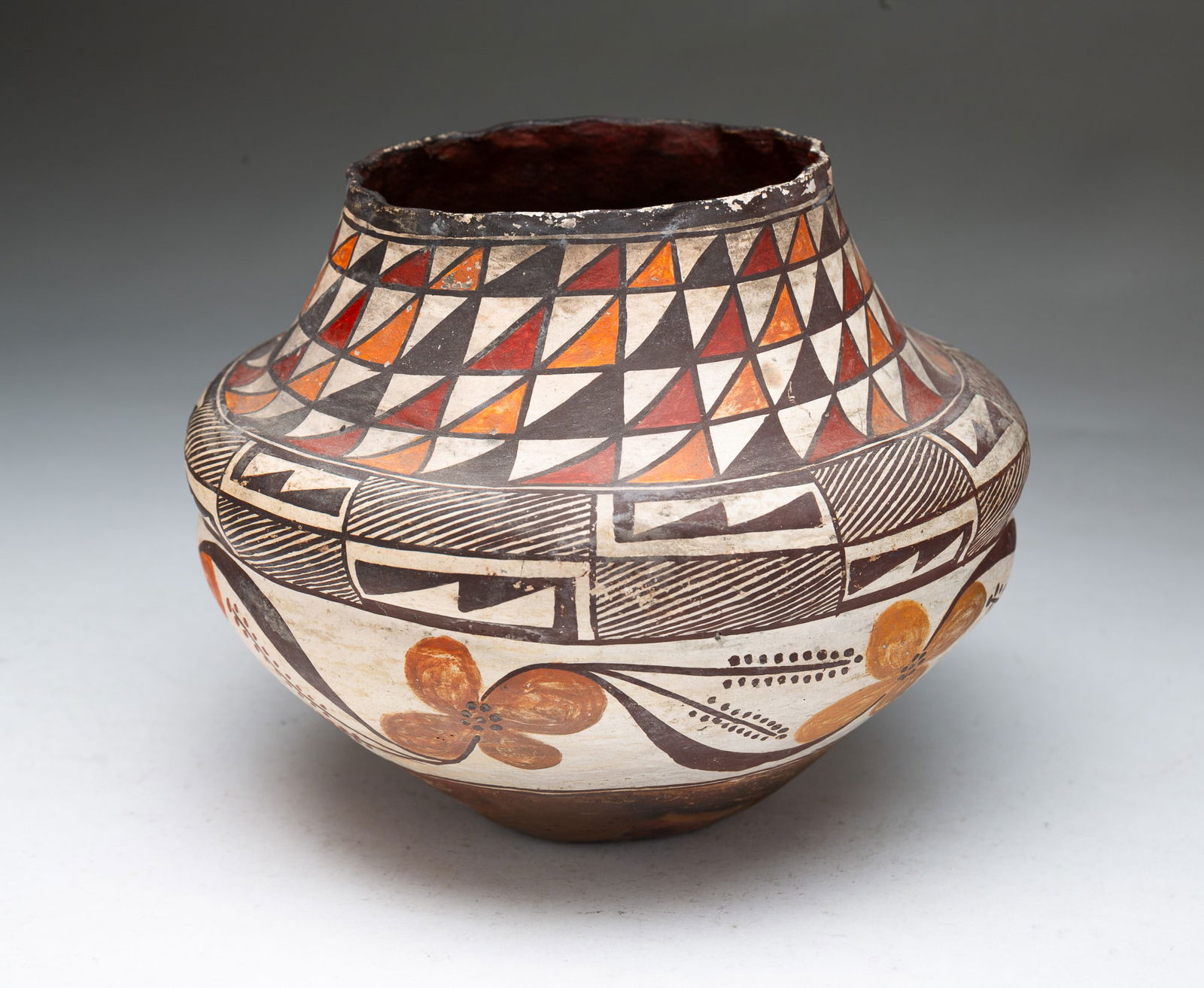 ACOMA PUEBLO POLYCHROME POTTERY OLLA JAR.: Acoma Pueblo (New Mexico), Early 20th Century. Thin-walled pottery vessel decorated in brown, white, orange, and red geometric designs and flowers, having a ruffled top rim and rib at waist. 6"h. 7"d.