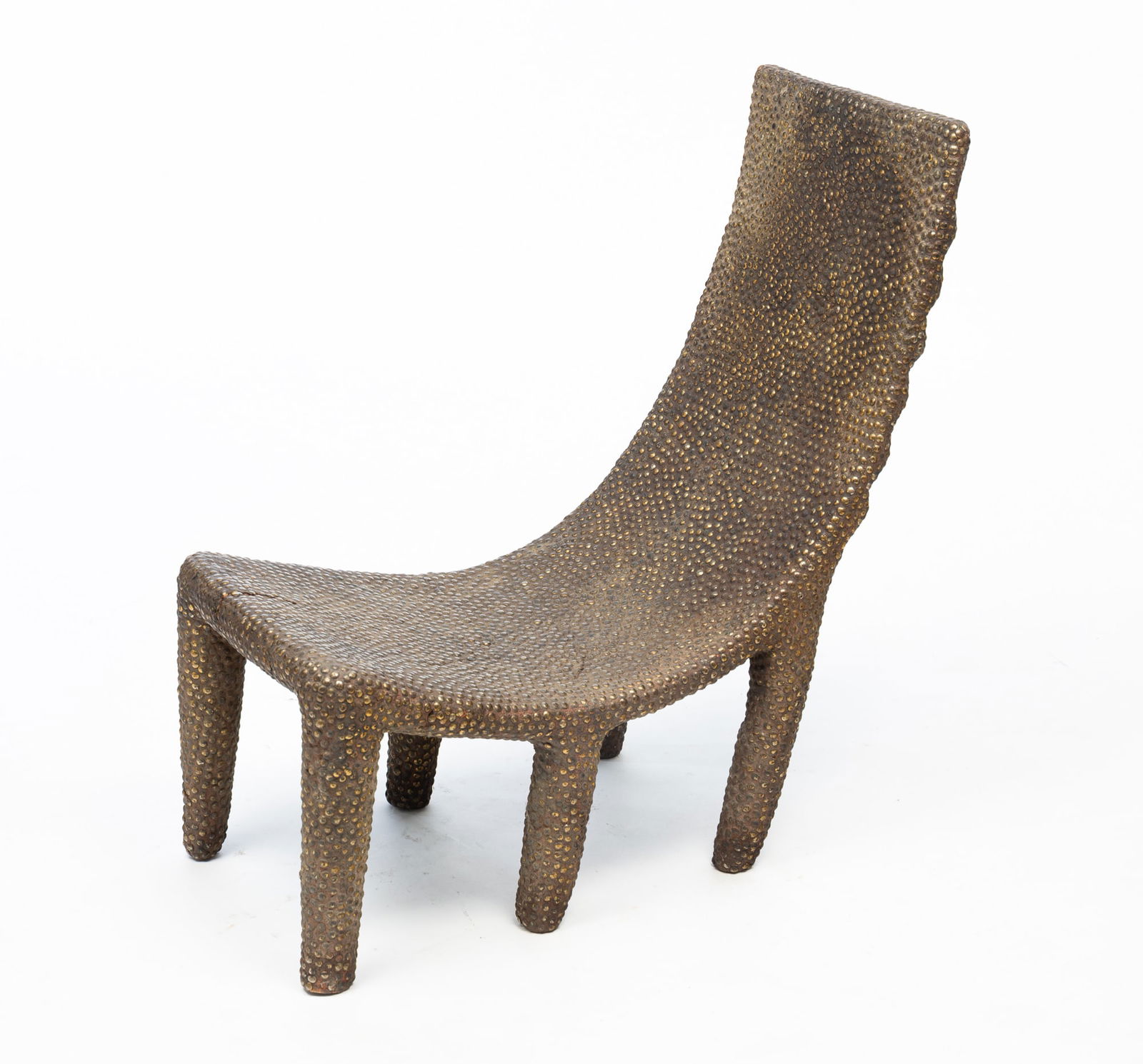 AFRICAN NGOMBE CHAIR.: Democratic Republic of Congo, 20th Century. Clay covered wood with brass nail head "upholstery". Rectangular curved seat, six cylindrical, slightly tapered legs and all over brass nail head decoration