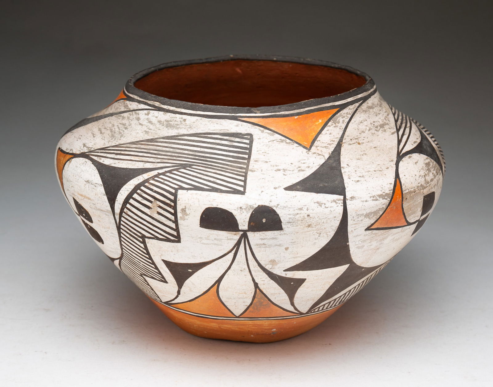 ACOMA PUEBLO POLYCHROME POTTERY OLLA JAR.: Acoma Pueblo (New Mexico), Early 20th Century. Thin-walled pottery vessel with sloped shoulder and tapered body, decorated in black, white, and orange geometric and botanical designs. 6.5"h. 9"d.Prove