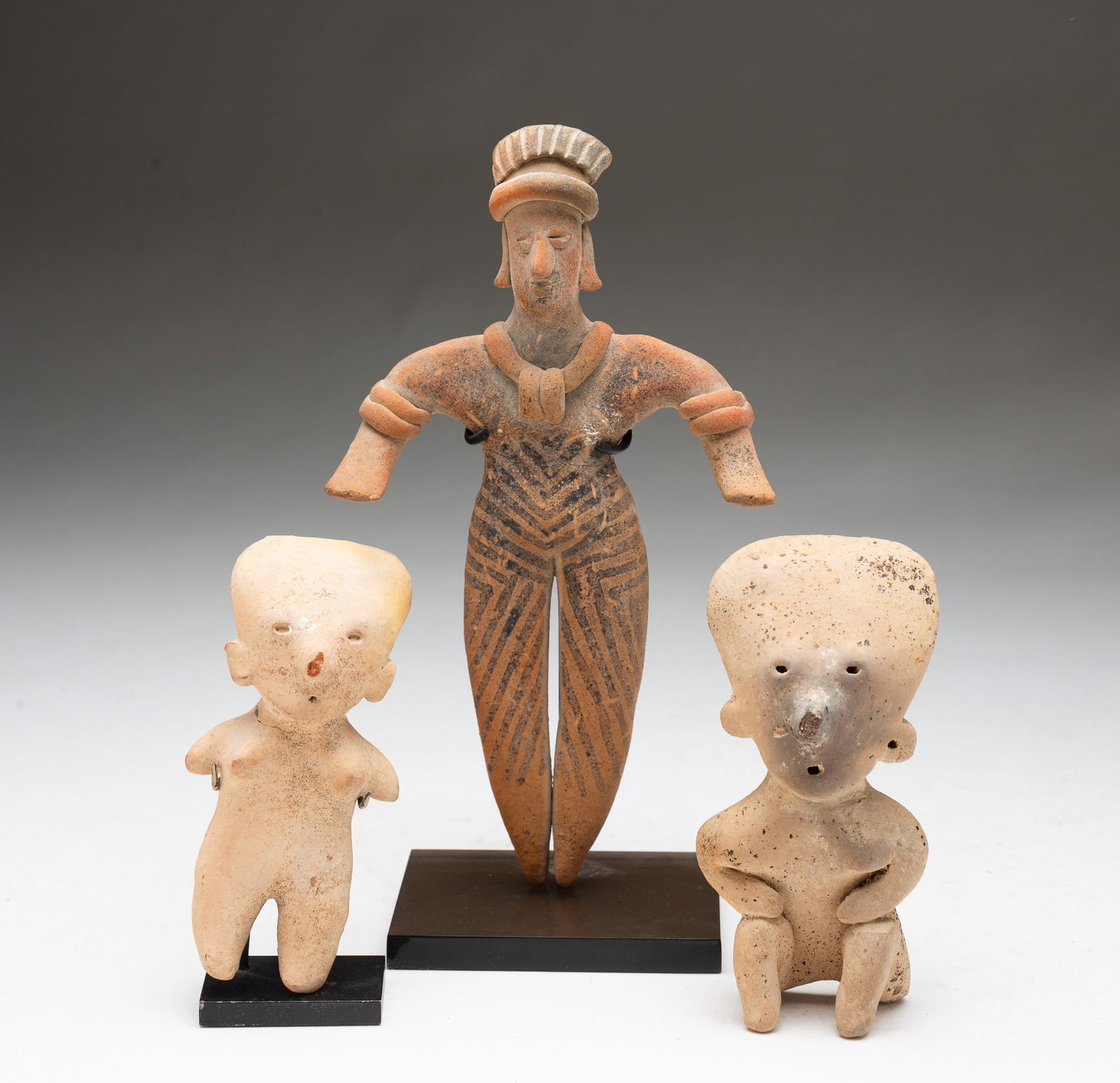 THREE POTTERY FIGURES FROM WEST COAST MEXICO.: West Coast Mexico. Two Nayarit Chinesco style figures, one seated, 4.5"h., and one on stand, 4.6"h. Together with a Colima Flat standing figure on stand, 8.25"h. 4.5"w.