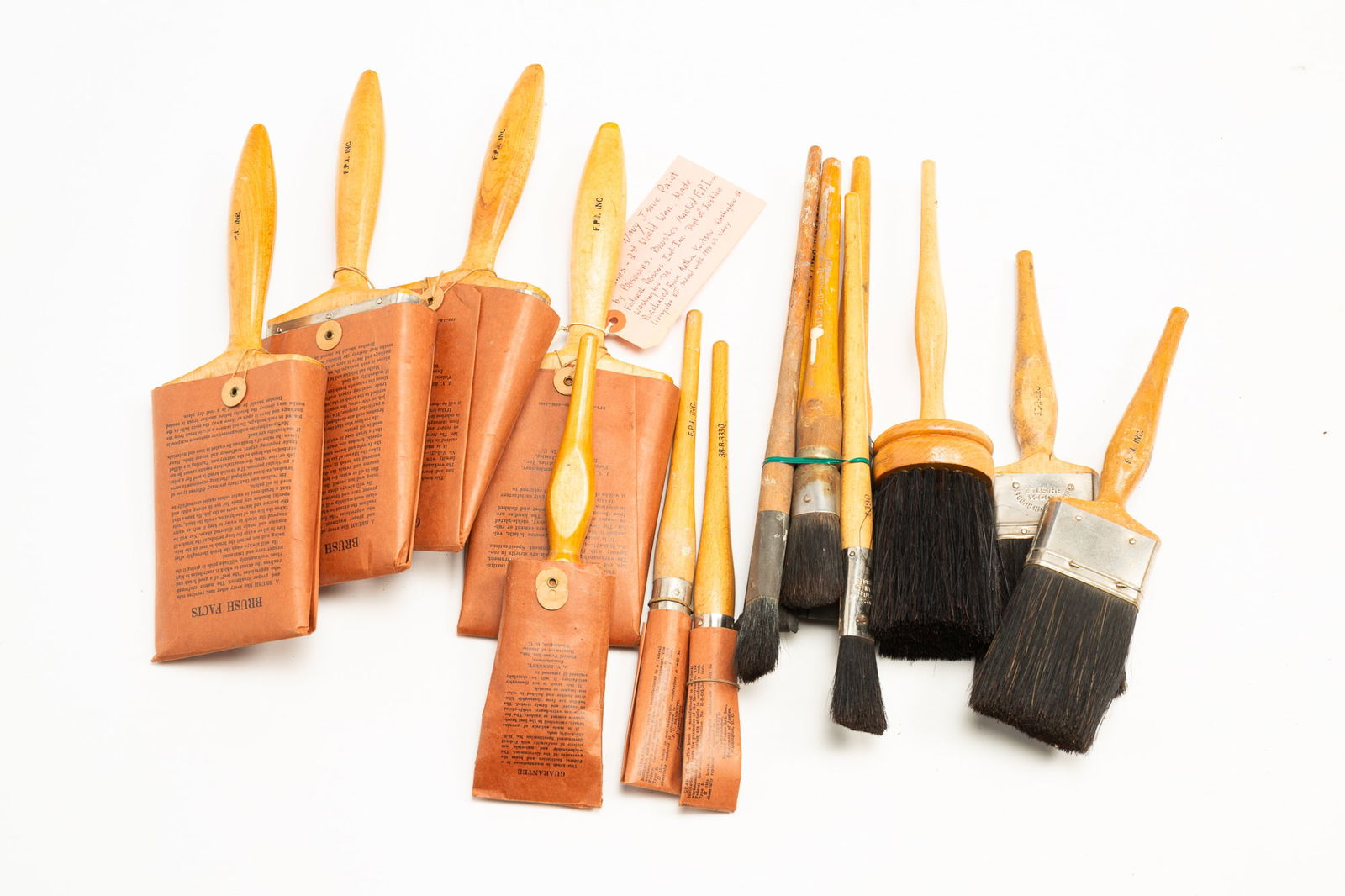 GROUP OF FIFTEEN PAINT BRUSHES MADE BY NAVY PRISONERS.: American, 1940s. Collection of paint brushes issued by the Navy, made by prisoners, most marked F.P.I. Inc. for Federal Prison Industries, Inc., and most with a paper covers having further information