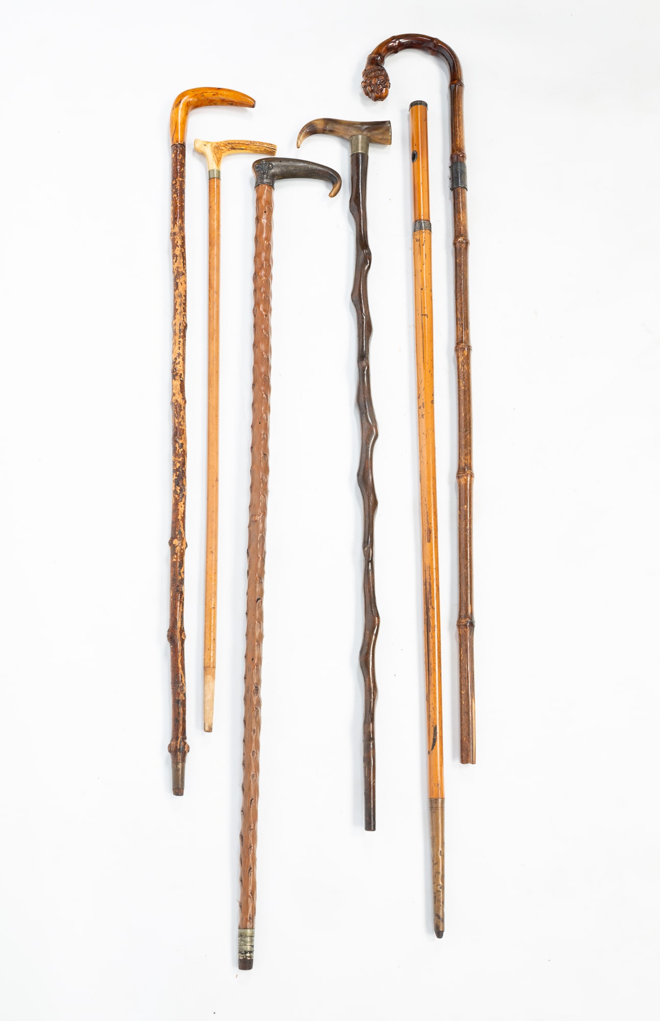 GROUP OF SIX FOLK ART CANES OR WALKING STICKS.: American, 20th Century. Two knotty wood sticks, a twisted root cane, a bamboo cane and a sword cane. Featuring handles in bone, horn and wood. From 27"l. to 36.5"l.Provenance: From the Lifetime Collec