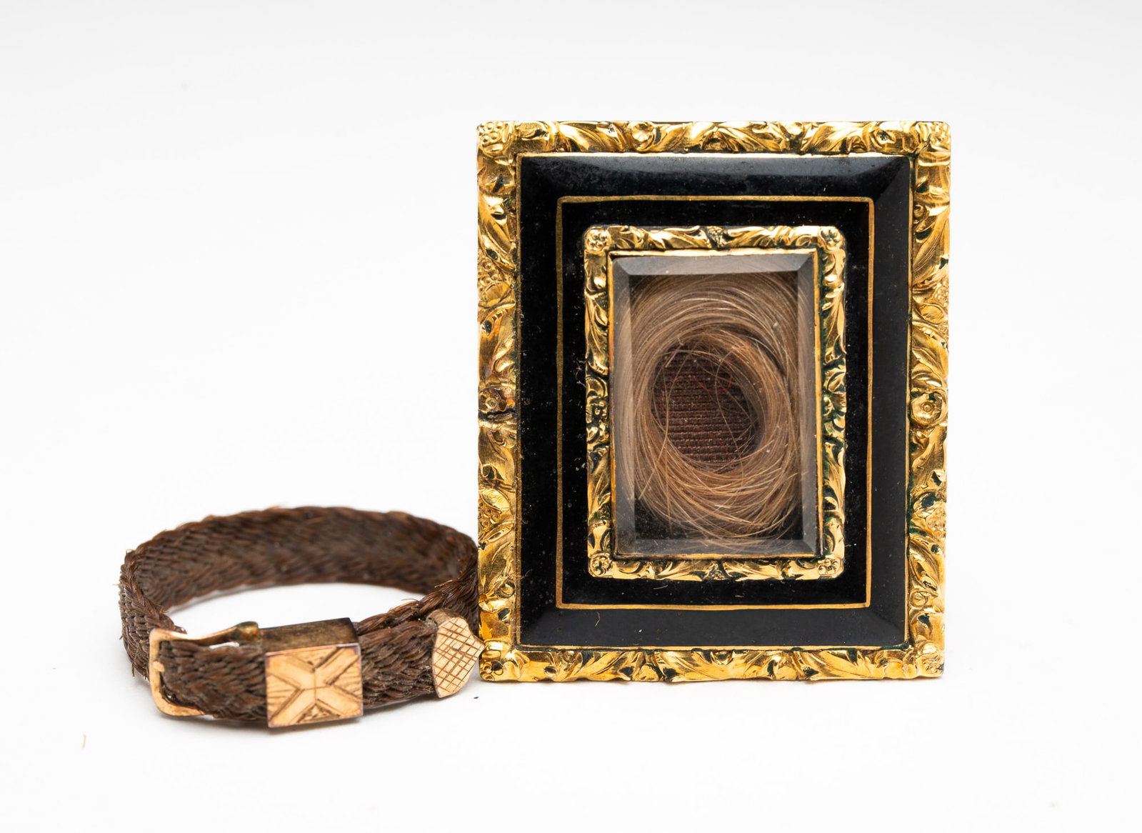 MOURNING JEWELRY BROOCH AND RING.: American, 19th Century. Gold and onyx brooch set with a ring of hair under a viewing window, straight pin and c-catch, and engraved "Nancy D. Blake 1838" on back. 1"h. 1.25"w. Together with a braided 