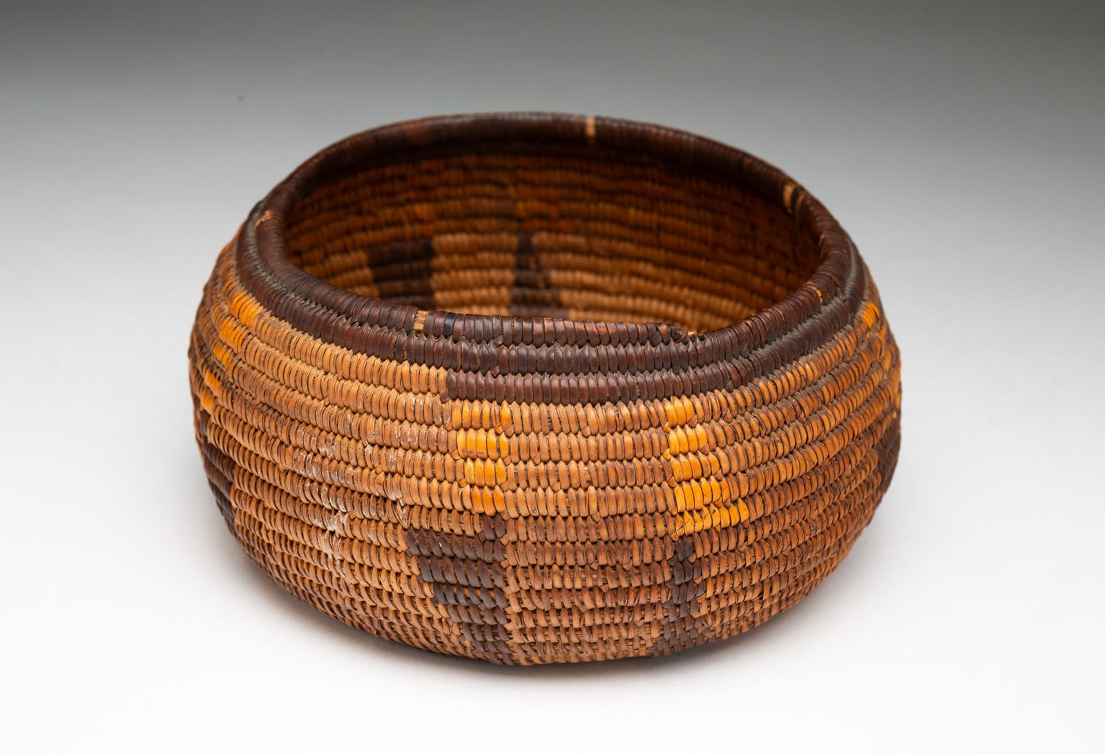POMO (CALIFORNIA) WOVEN BASKET.: Pomo (California), Early 20th Century. Circular, tightly woven coiled basket having geometric designs. 3"h. 6.25"d.Provenance: From the Lifetime Collection of the late Ken Hanna (Chester, New Jersey).