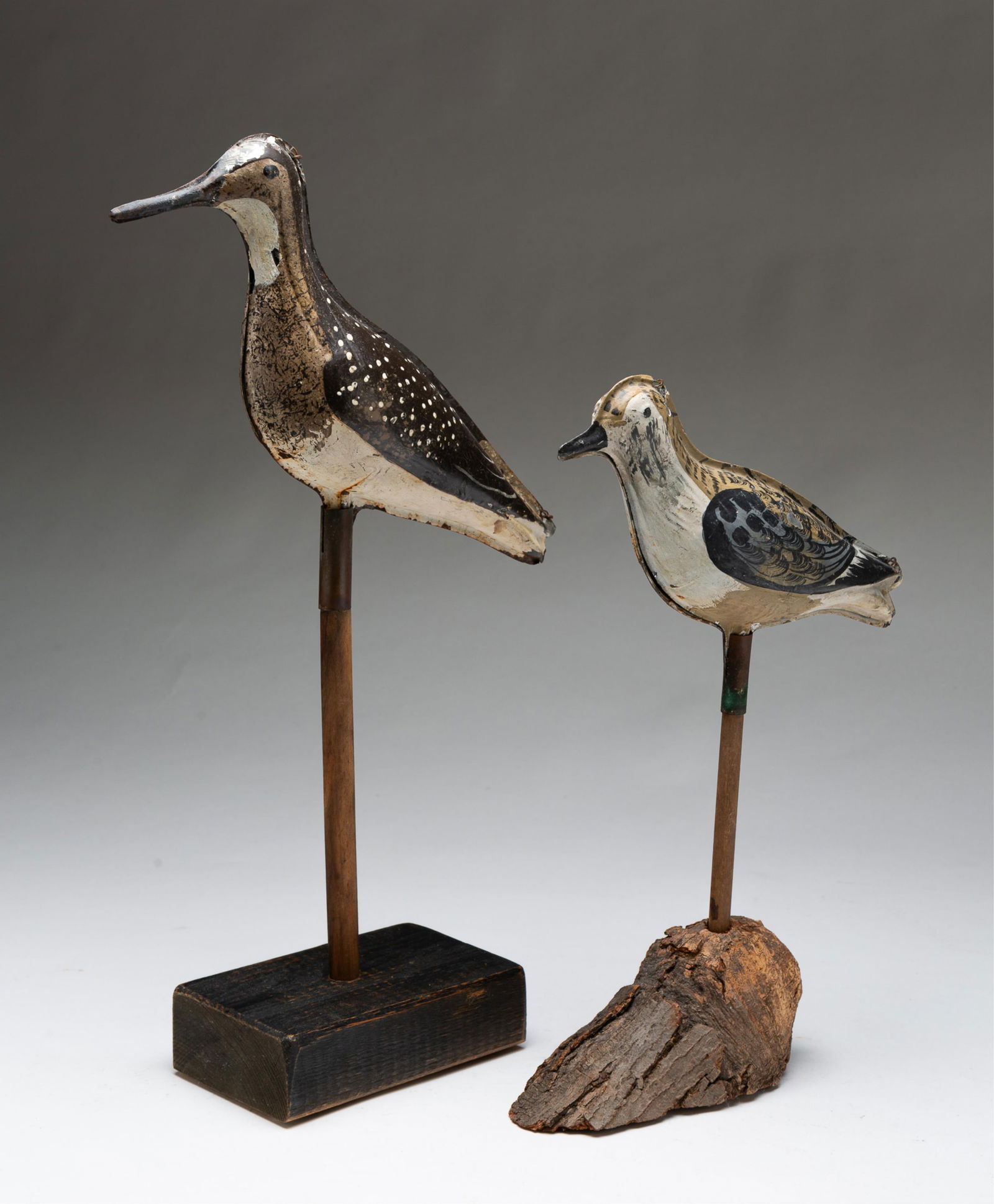 TWO AMERICAN PAINTED TIN SHOREBIRD DECOYS.: American, ca. 1900. Each die-pressed in two sections with worn brown, black, and white paint, the first on a wooden dowel rod mounted to a tree knot and the second on a wooden dowel rod mounted into a