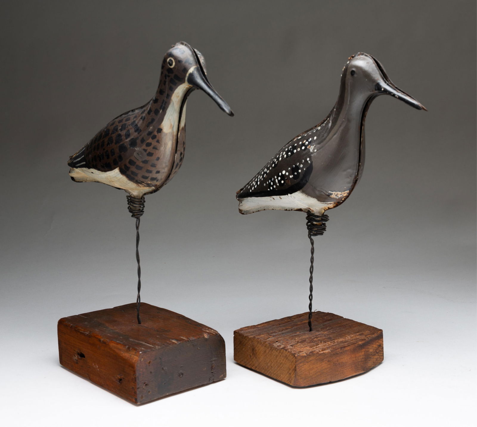 TWO AMERICAN PAINTED TIN SHOREBIRD DECOYS WITH PINE STANDS.: American, ca. 1900. Each die-pressed in two sections with worn brown, black, and whitepaint, on pine block stands supported by twisted metal wire. The taller, 13.25"h.