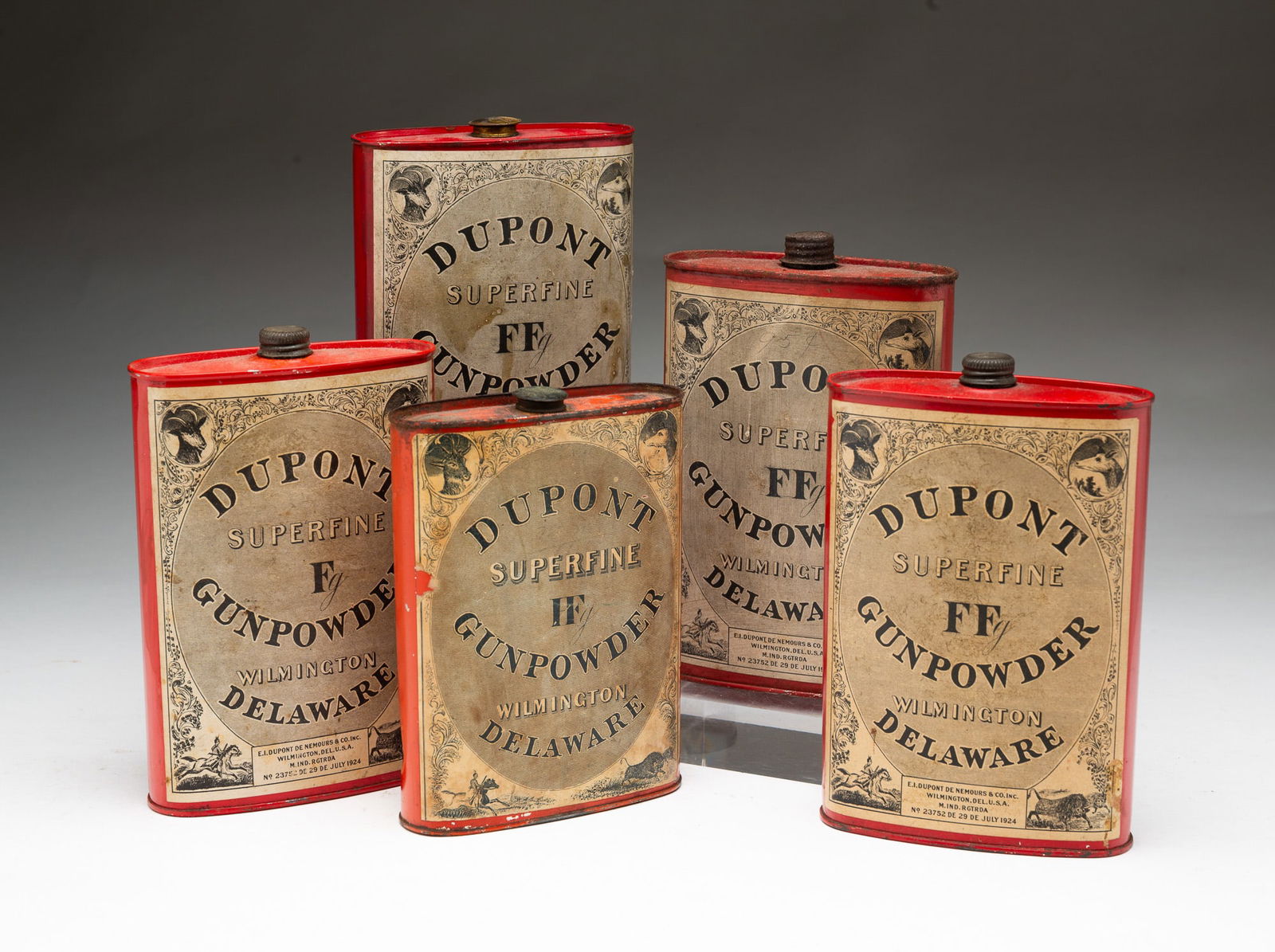 FIVE DUPONT (WILMINGTON, DELAWARE) TIN SUPERFINE GUNPOWDER FLASKS.: E.I. Dupont De Nemours & Co. Inc. (Wilmington, Delaware), Early 20th Century. Tin. Each having a twist-off cap above a flask-shaped body with paper label reading "DUPONT / SUPERFINE / GUNPOWDER / WILM