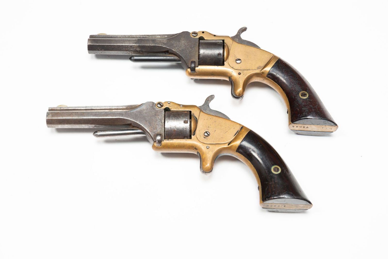 TWO SMITH AND WESSON MODEL ONE SECOND ISSUE REVOLVERS.: American, Second half 19th Century. Octagonal barrel, single action, brass frame, 22 caliber and serial numbers 76864 and 107722. 6.75"l.