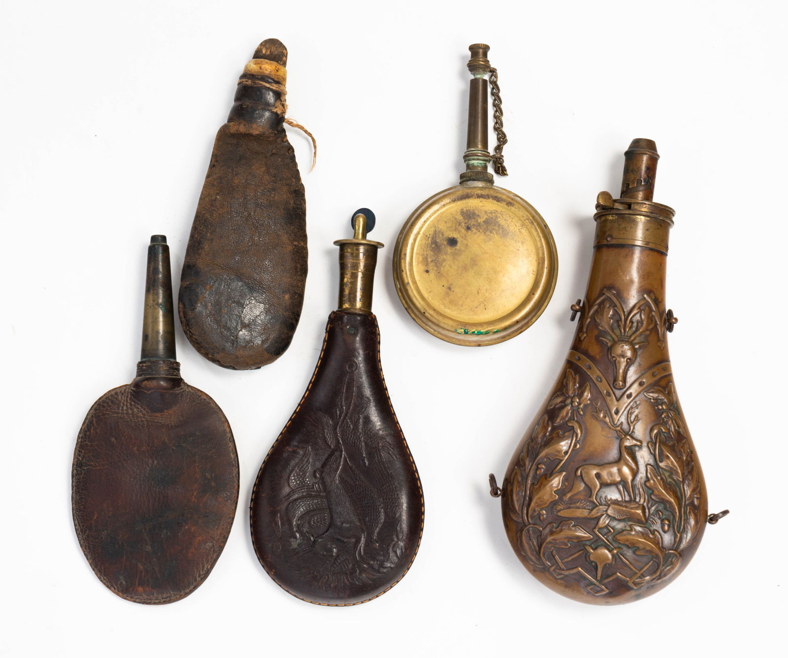 FIVE AMERICAN SHOT FLASKS.: American, 19th Century. Decorated brass powder flask by The American Flask & Cap Company (marked "AM Flask & Cap. Co") with relief-embossed oak leaf, acorn and stag decoration, 8.5"h. Plain brass with