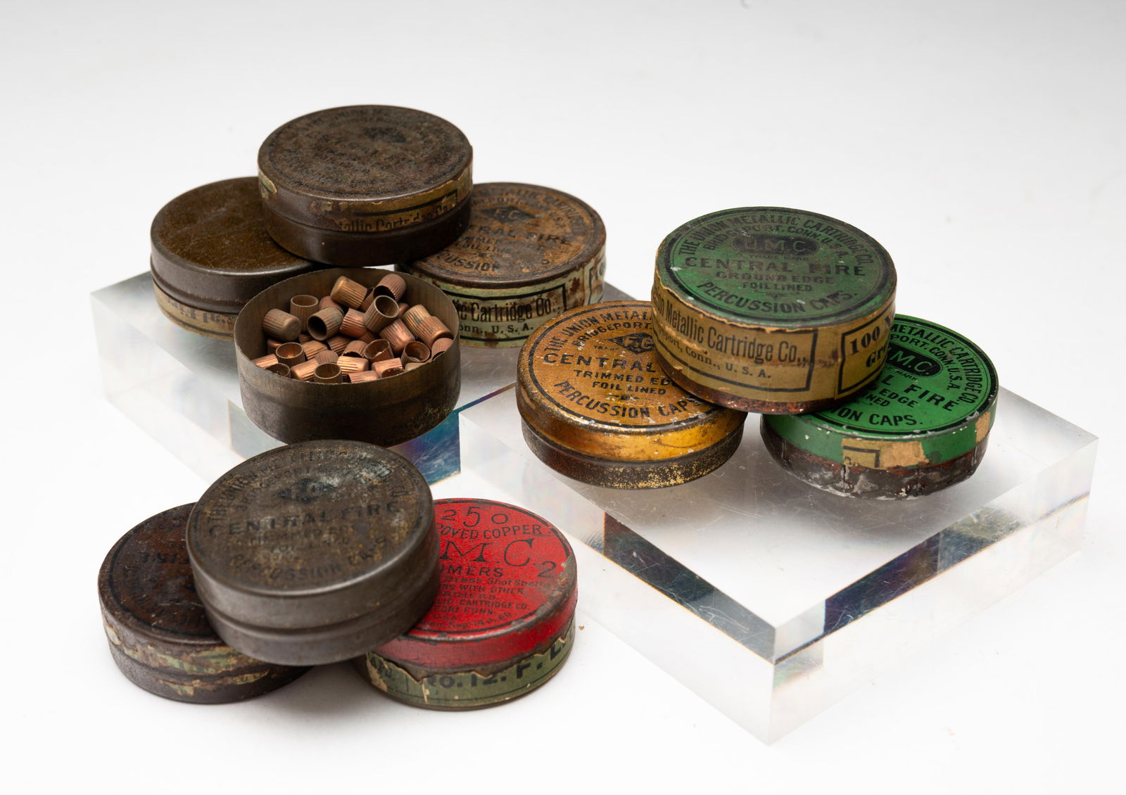 TEN AMERICAN U.M.C. PERCUSSION RIFLE CAP TINS.: American (Bridgeport, Connecticut), Late 19th Century. Red, green and gold labels, some unopened. 5"h. 1.5"d.