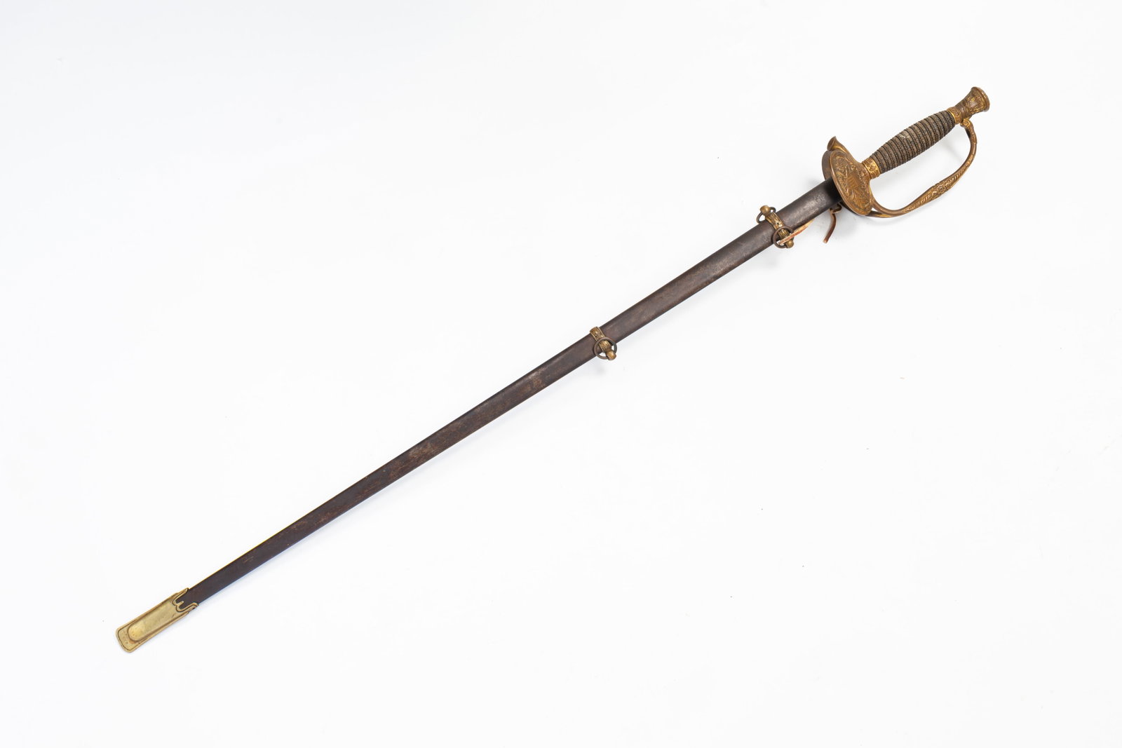AMERICAN CIVIL WAR ERA OFFICERS SWORD AND SCABBARD.: American, 19th Century. Braided wire wrapped sharkskin handle, crown top front of hilt with eagle and banners, reverse with shield and cannons, tapered thin blade and steel scabbard with brass tip and