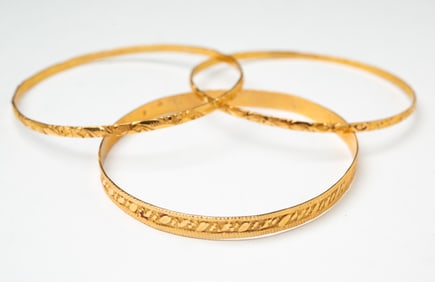 THREE 18K YELLOW GOLD BANGLES WITH BRIGHTWORK ENGRAVING.