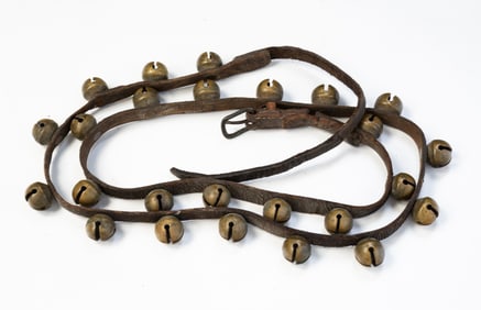 LEATHER STRAP WITH TWENTY-FIVE BRASS SLEIGH BELLS.