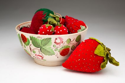 ENGLISH PEARLWARE BOWL FILLED WITH STRAWBERRY-FORM EMERIES AND PIN CUSHIONS.