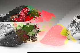 ENGLISH PEARLWARE BOWL FILLED WITH STRAWBERRY-FORM EMERIES AND PIN CUSHIONS.: English and American, 19th Century. Bowl decorated with roses and strawberries, filled with nine strawberry emeries and twelve strawberry pin cushions. 22 items total. Bowl, 2.75"h. 5.75"d.Provenance: