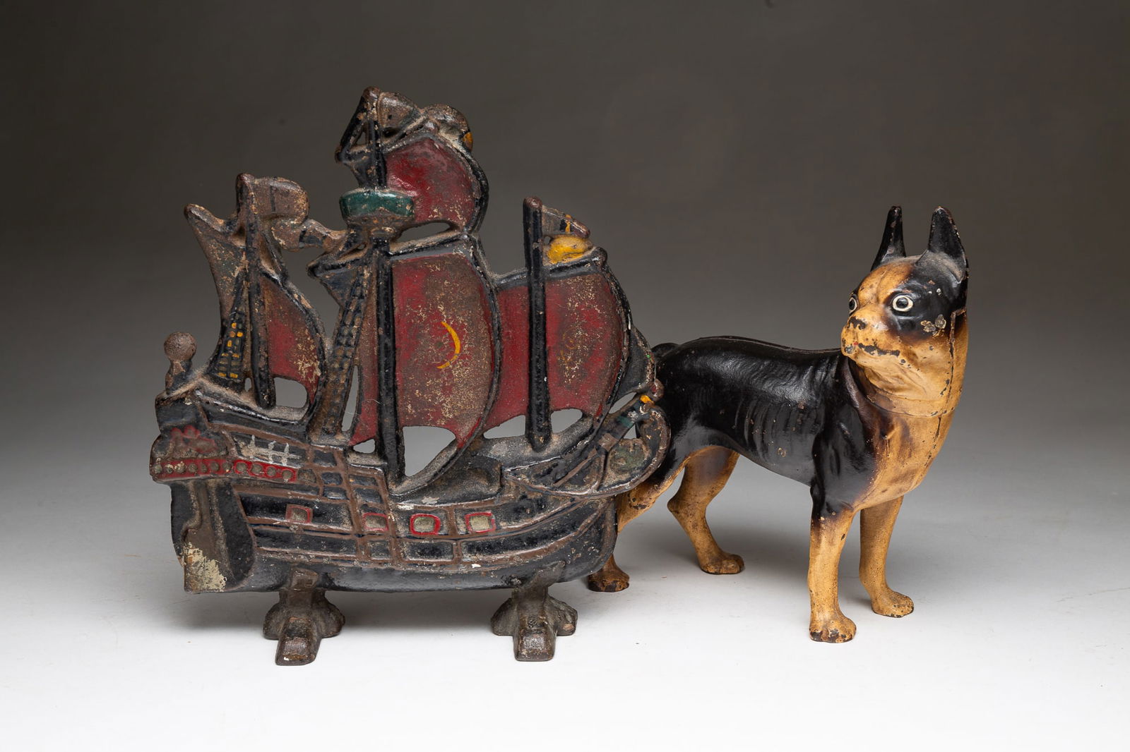 TWO AMERICAN CAST IRON DOORSTOPS.: Early 20th Century. A three masted galleon with original black, red and yellow paint. 11"h. 10.5"w. And a bull dog in black and white paint. 8.75"h. 8"w.