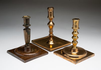 THREE SPANISH BRASS SQUARE BASE CANDLESTICKS.