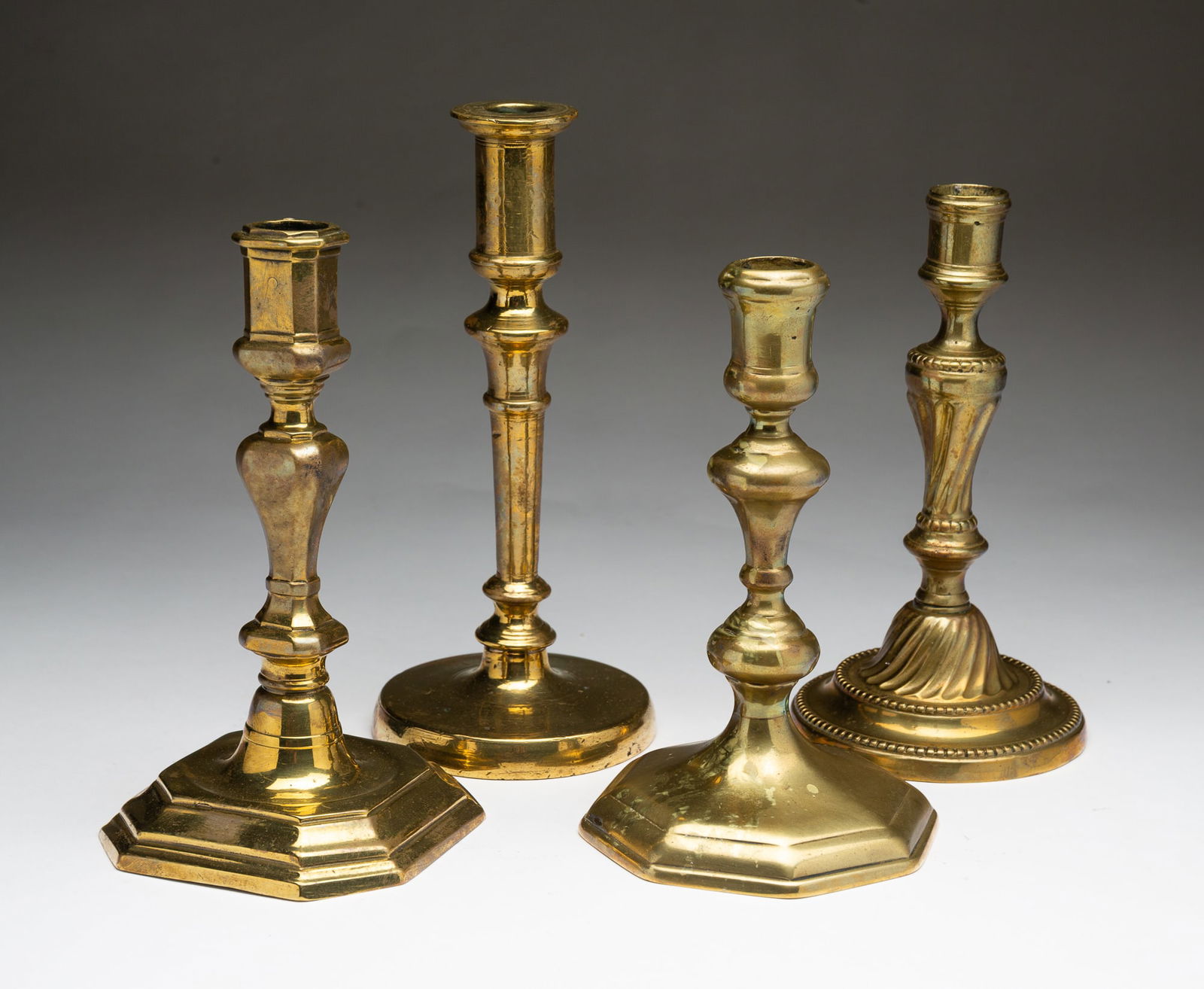 FOUR EUROPEAN BRASS CANDLESTICKS. (1 of 5)